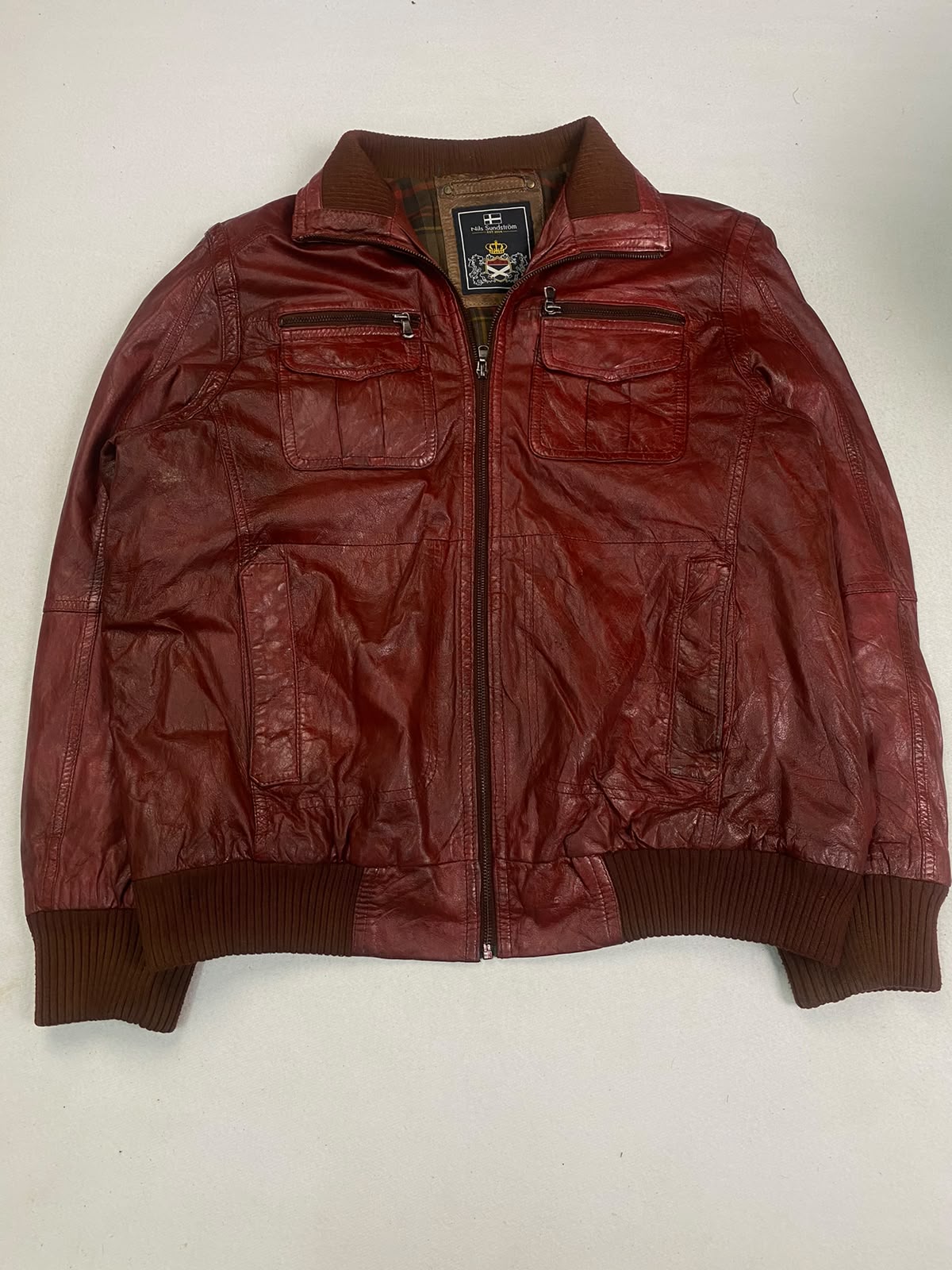 Red leather bomber jacket with a ribbed collar, cuffs, and waistband