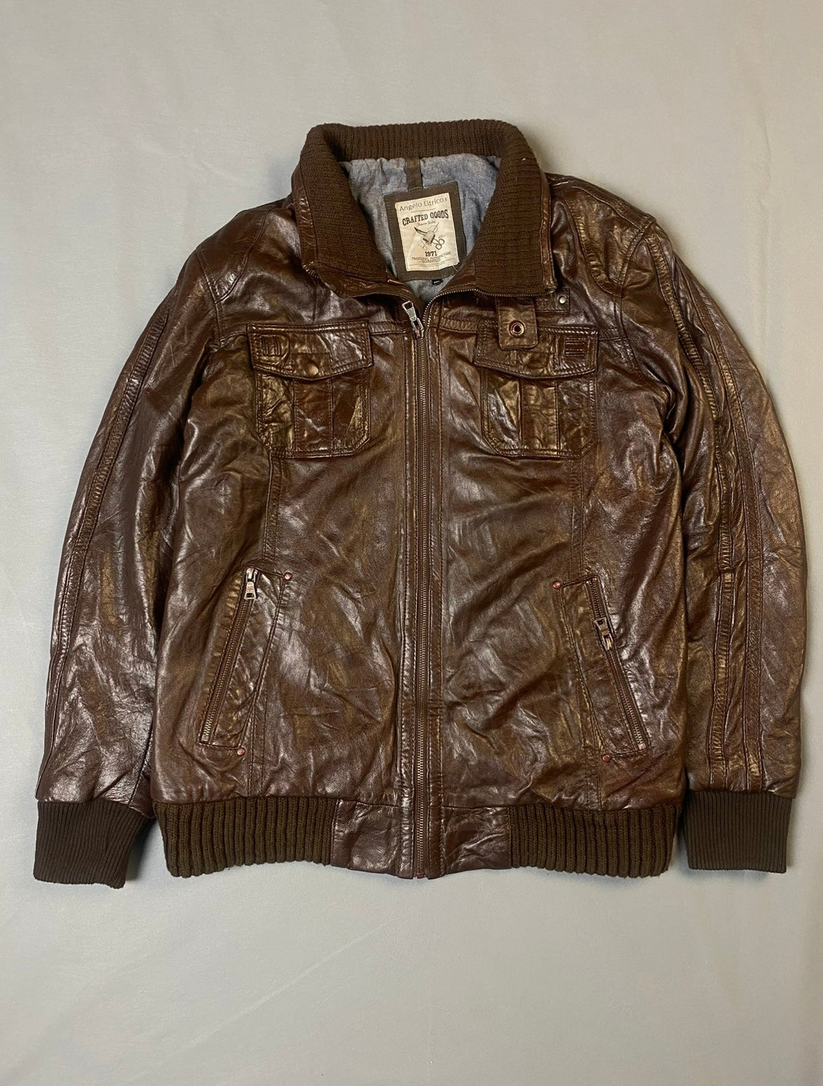Brown leather bomber jacket with chest flap pockets, ribbed collar, cuffs and hem