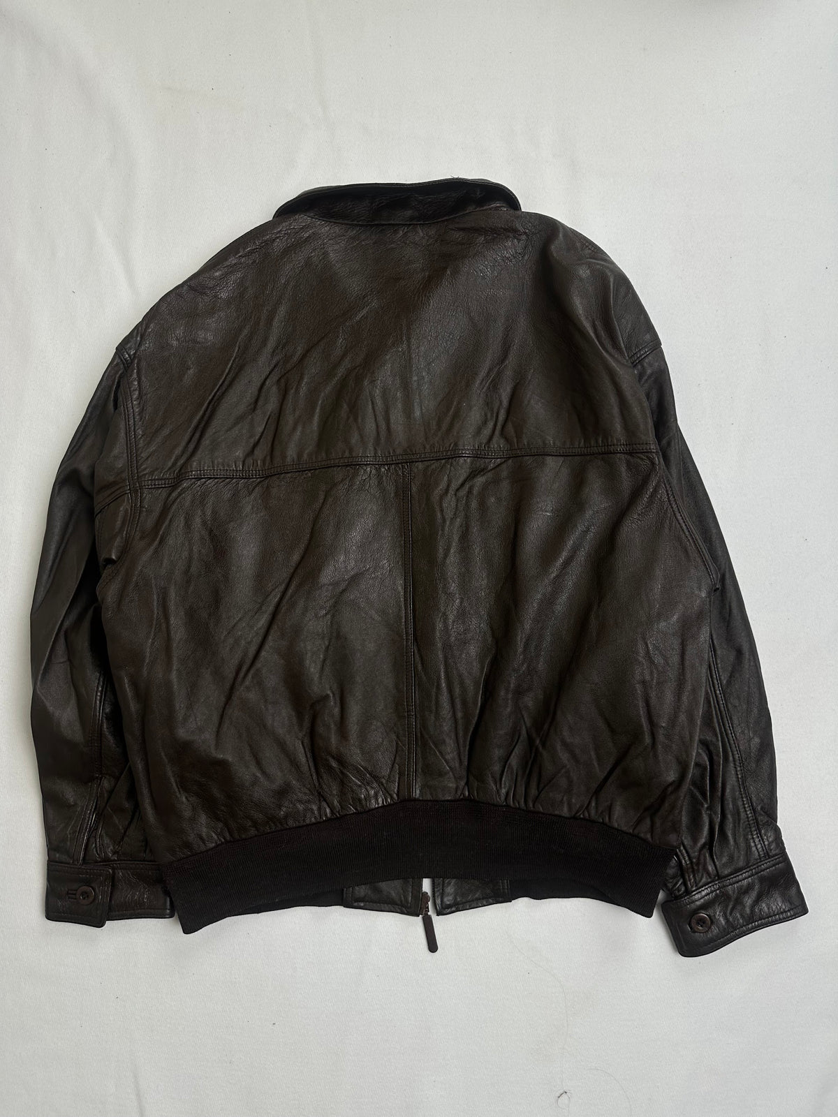 Pointed shirt collar latched at the throat on the brown flight jacket
