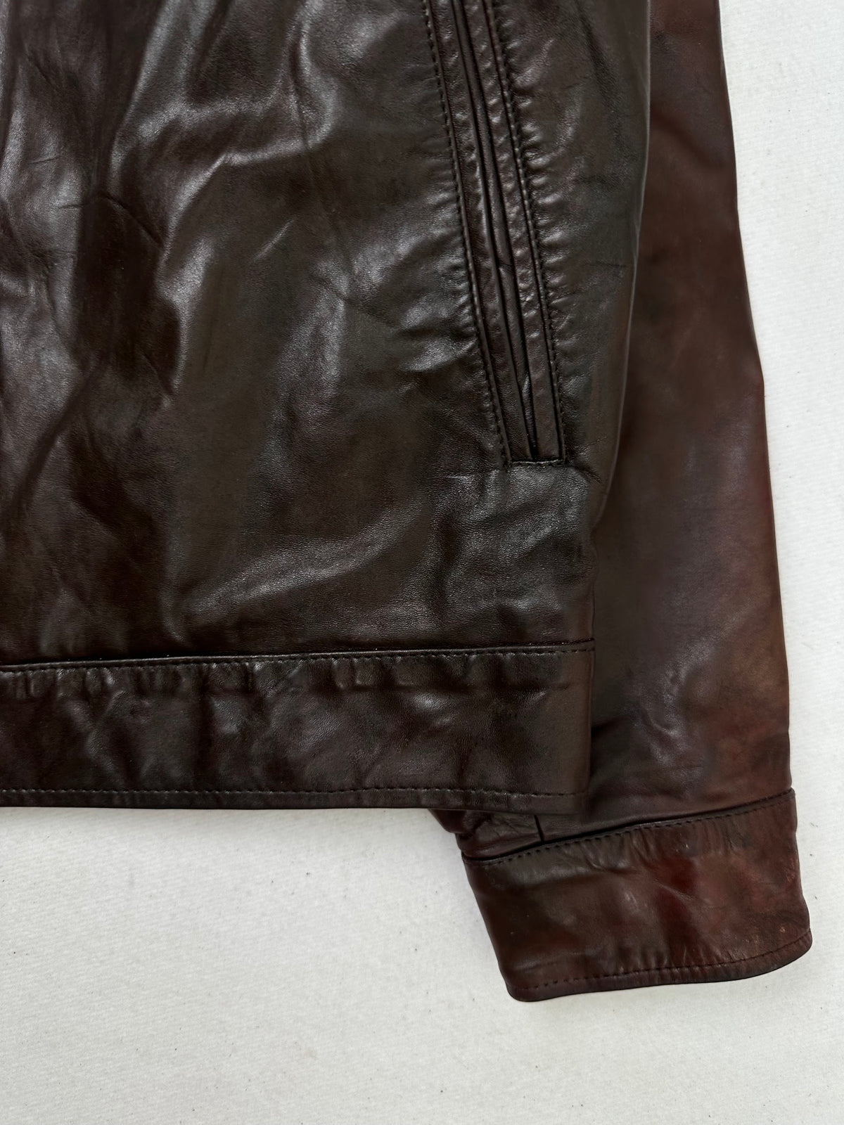 Side pocket and hem of the size S burgundy leather vintage jacket, up close