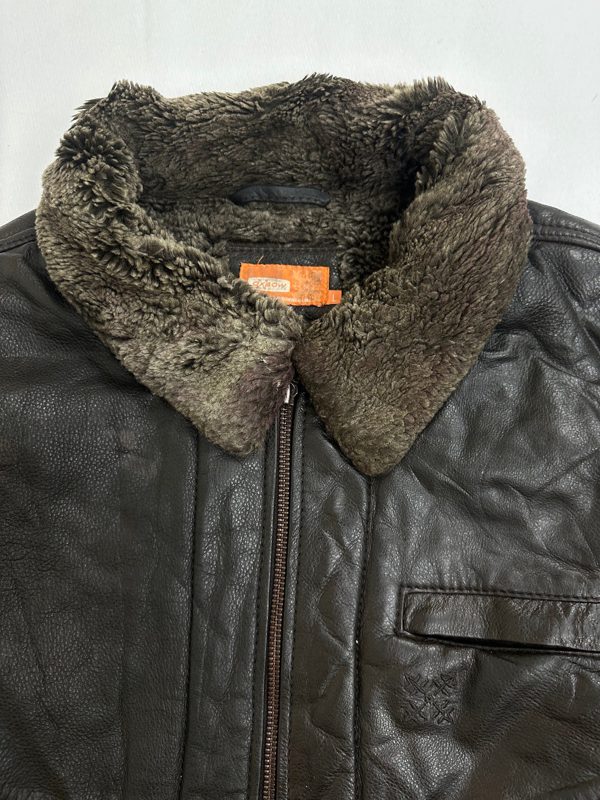 Shearling collar standing above the front zip on the brown flight jacket