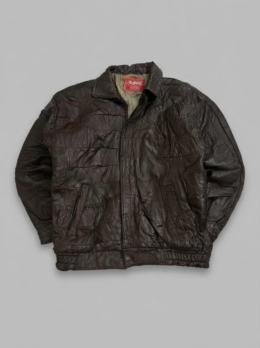 Brown patchwork leather harrington jacket laid flat, pointed collar, centre zip and elasticated leather hem band