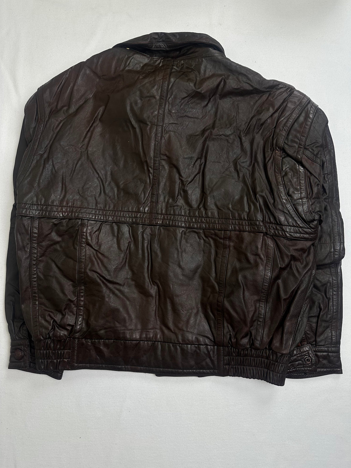 Tall padded stand collar open above the storm flap on the brown flight jacket