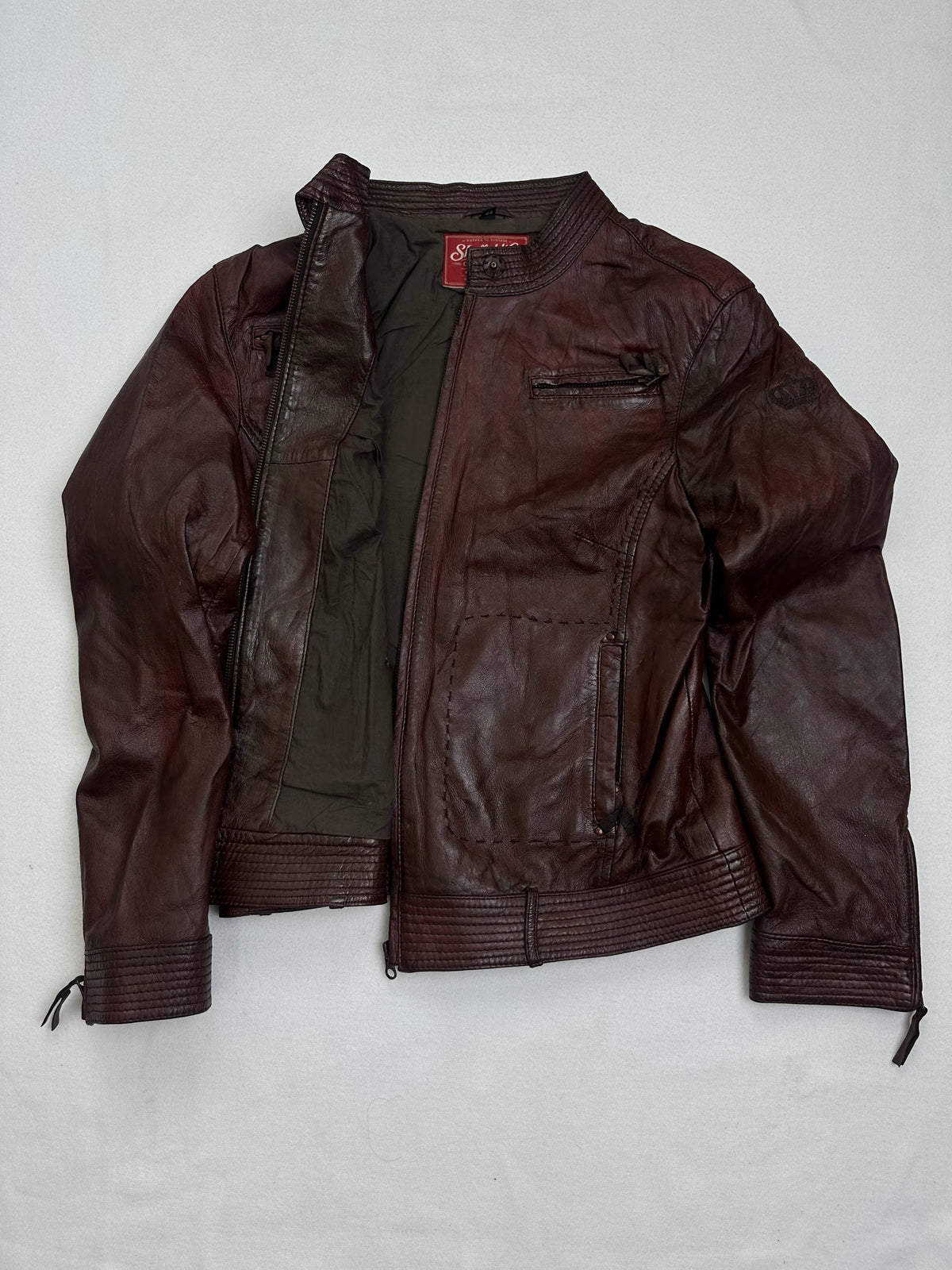 The size S burgundy leather cafe racer jacket opened to show the lining
