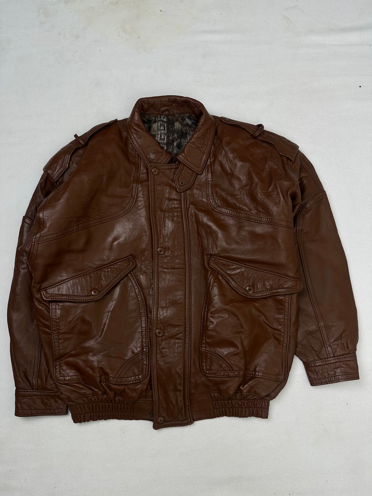 Front of the size L brown leather flight jacket, laid flat and unedited