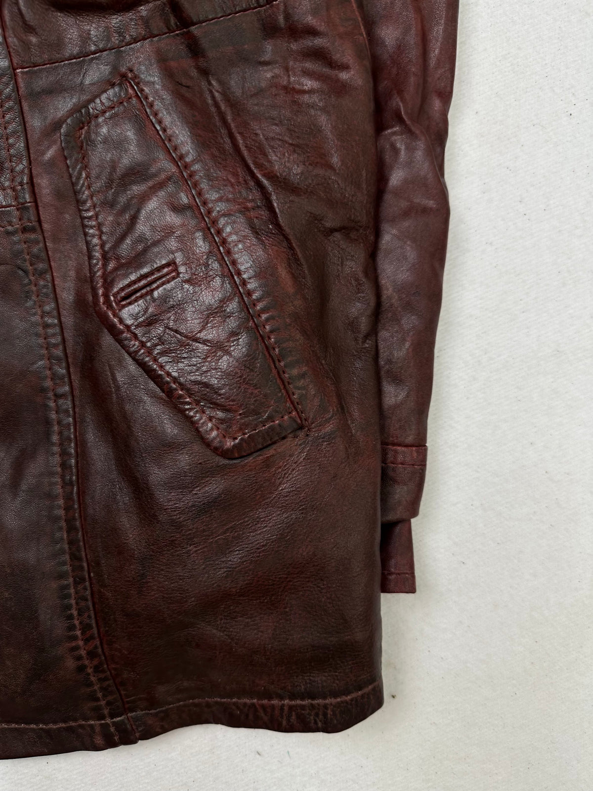 Side pocket and hem of the size L burgundy leather hooded jacket, up close