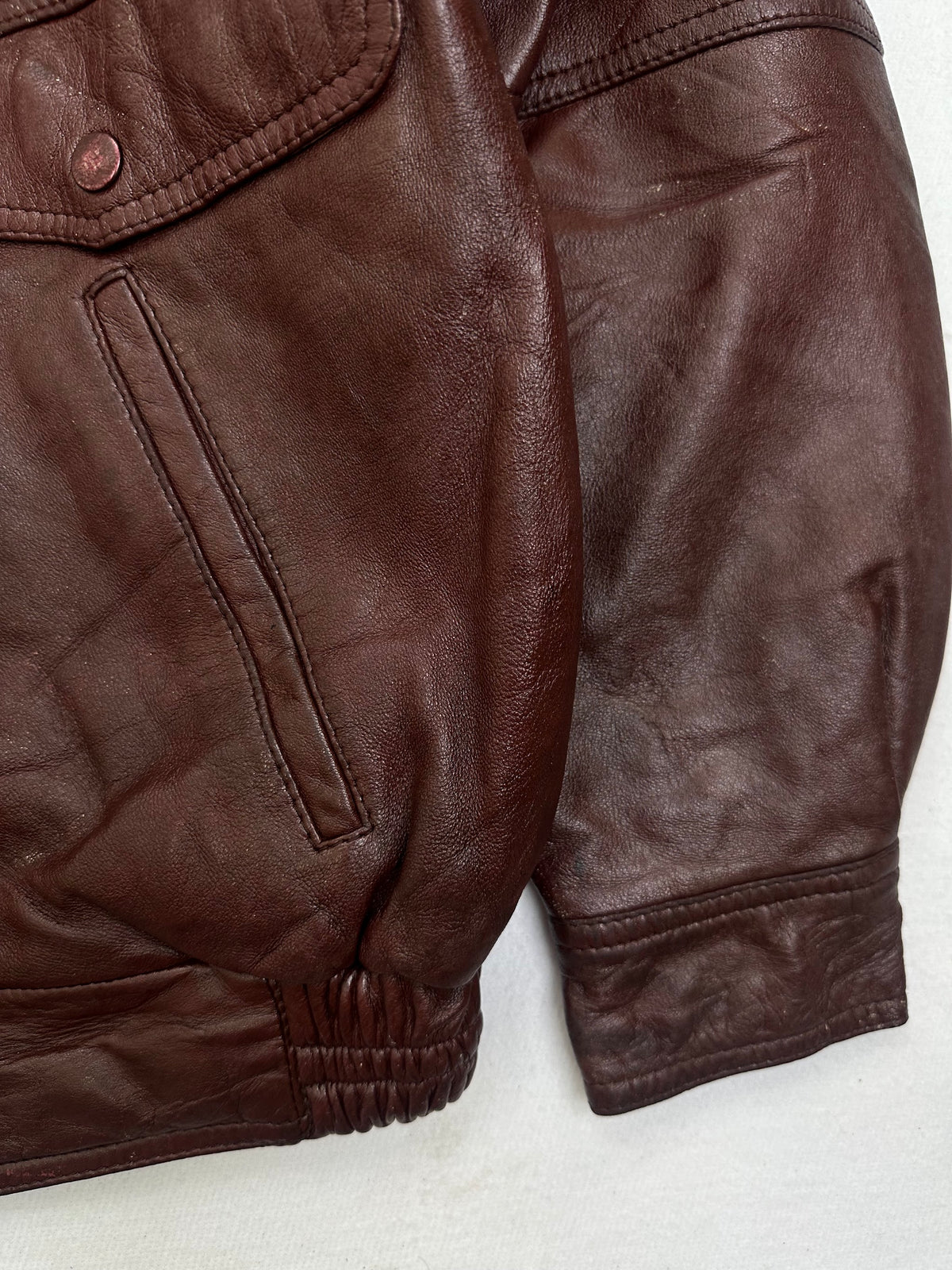 Side pocket and hem of the size L burgundy leather flight jacket, up close
