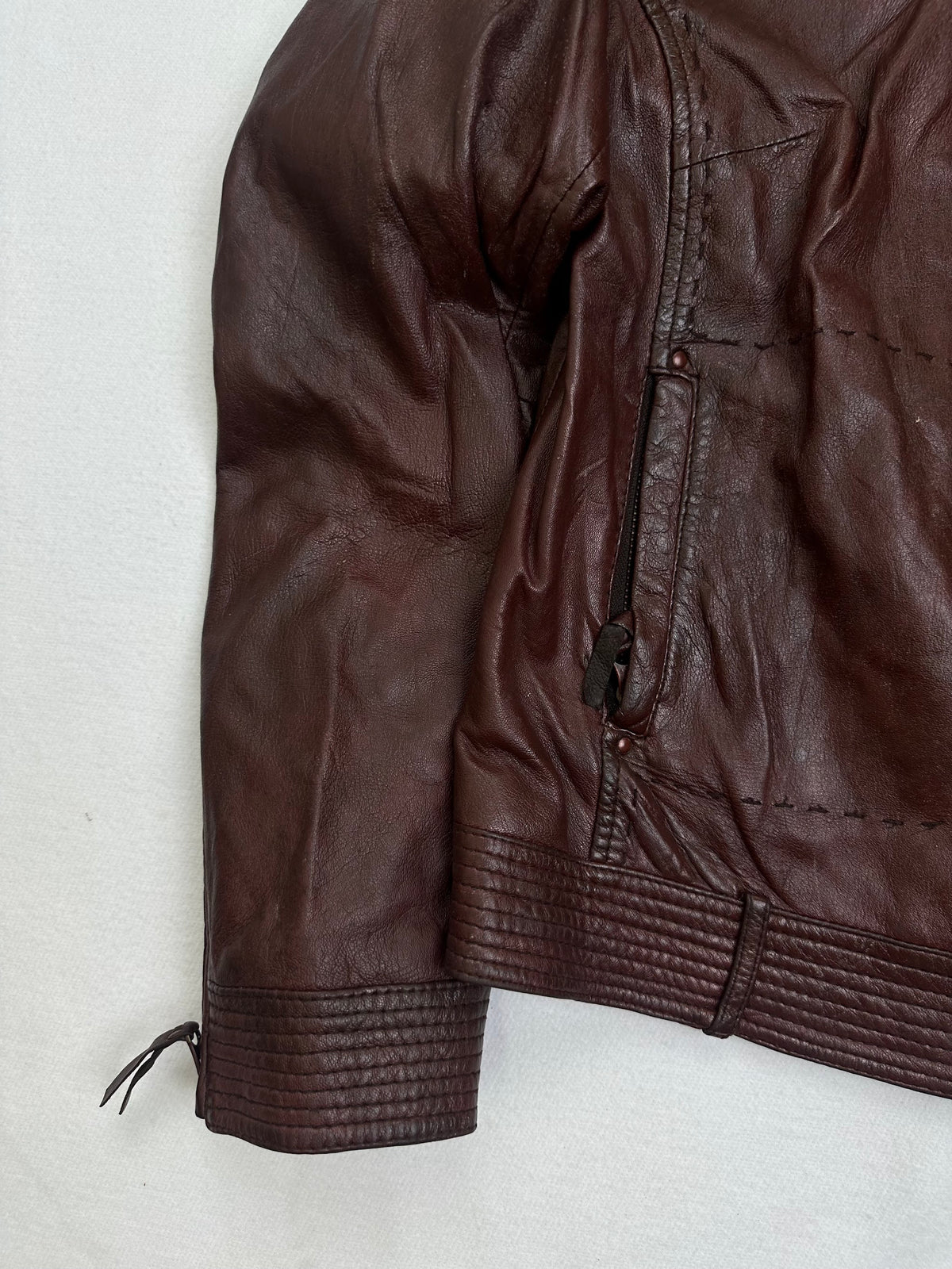Close detail of the pockets and cuff on the size S burgundy leather cafe racer jacket