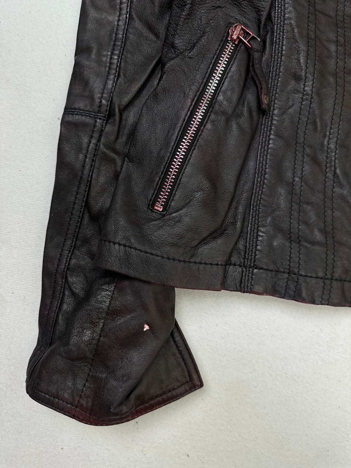 Close detail of the pockets and cuff on the size S burgundy leather cafe racer jacket
