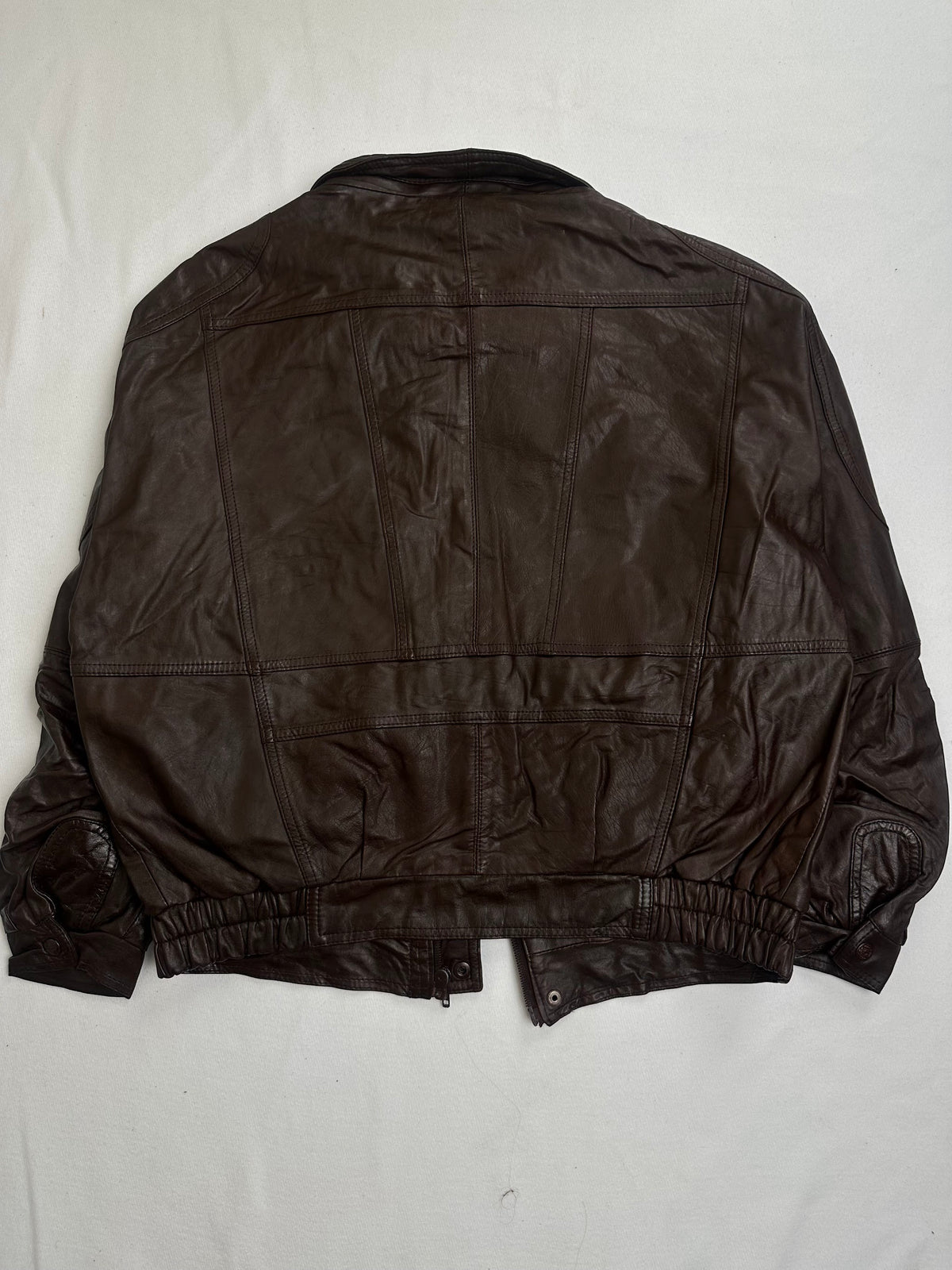 Leather storm flap snapping shut over the centre zip at the throat