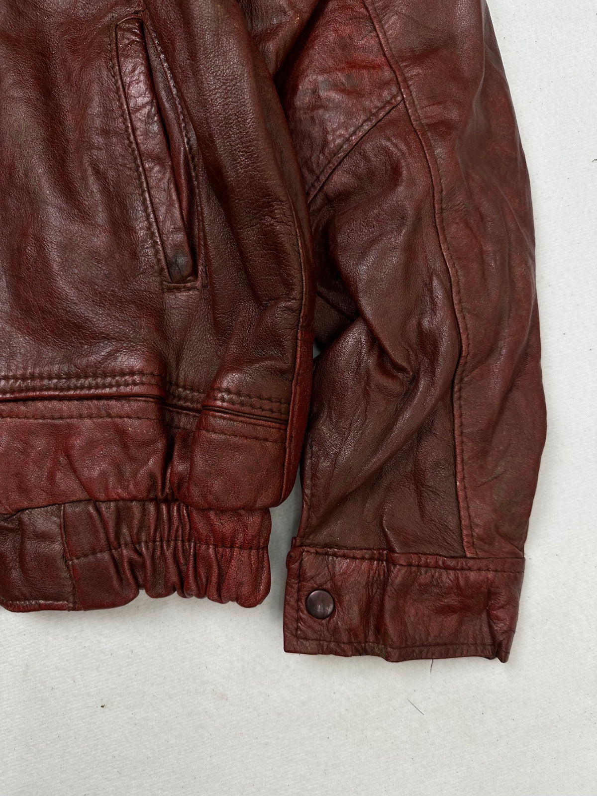 Side pocket and hem of the size L burgundy leather flight jacket, up close