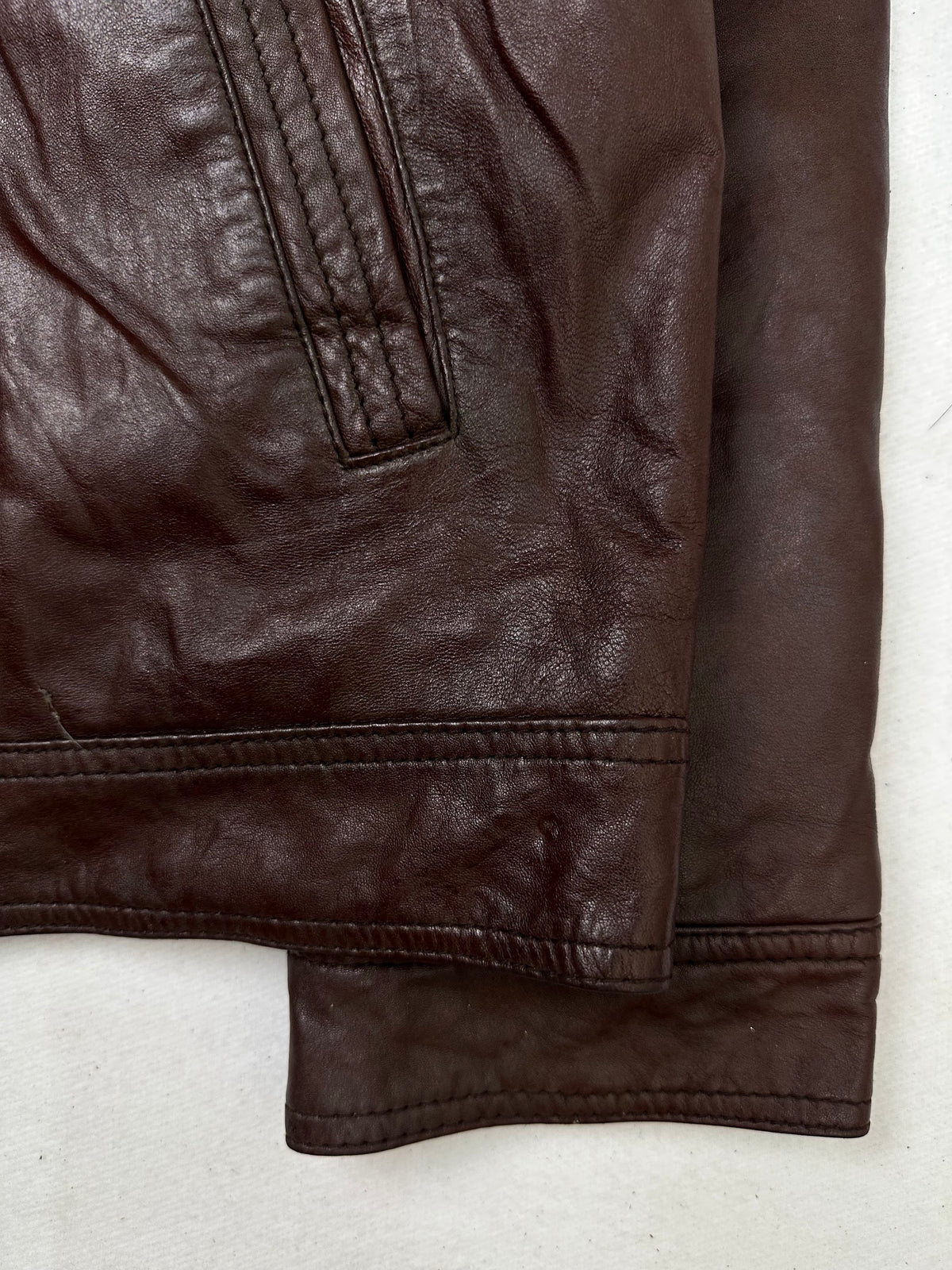 Side pocket and hem of the size L burgundy leather cafe racer jacket, up close