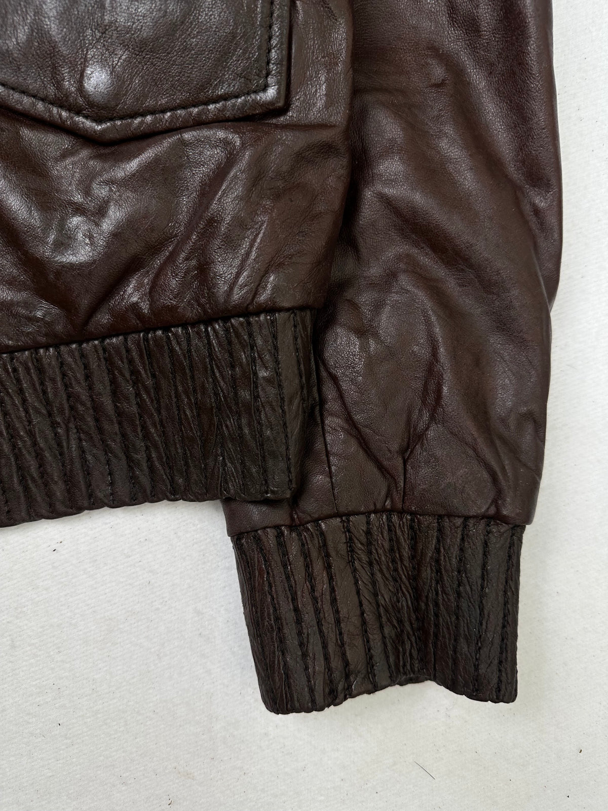 Side pocket and hem of the size S burgundy leather flight jacket, up close