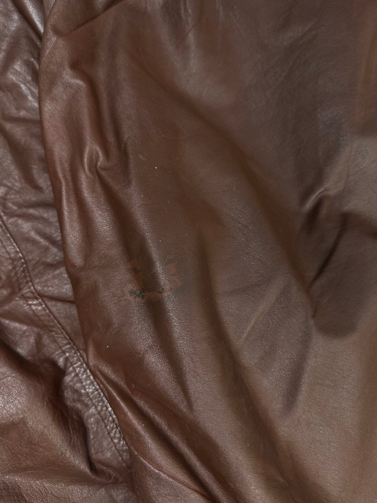 A small mark on the sleeve of the size XL burgundy leather vintage jacket, shown up close