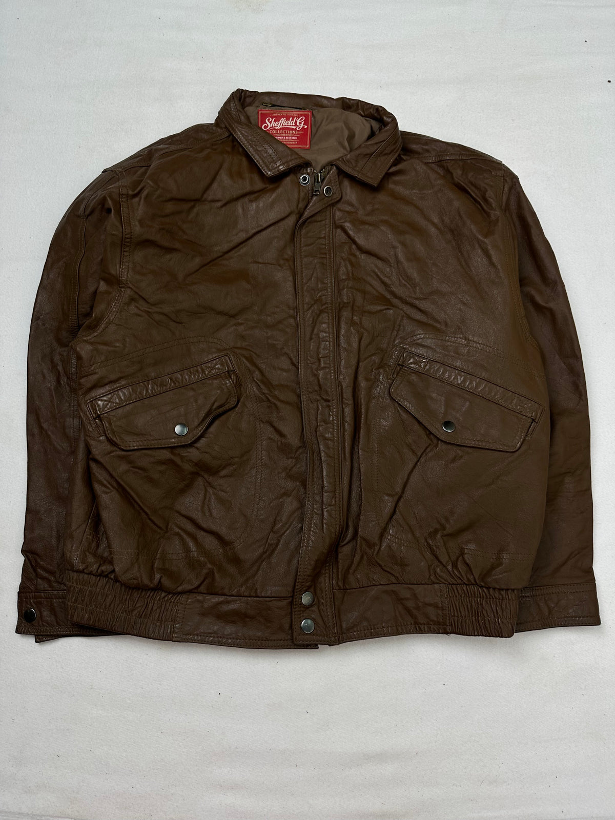 Front of the size M brown leather flight jacket, laid flat and unedited