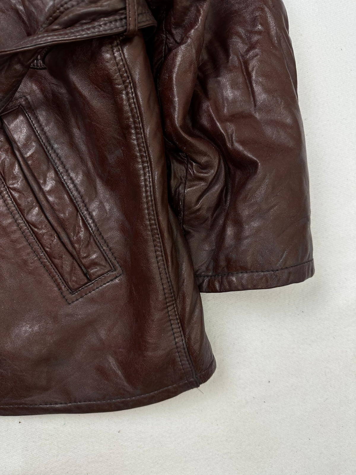 Side pocket and hem of the size M burgundy leather vintage jacket, up close