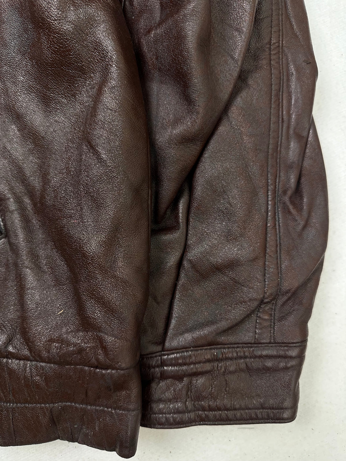 Side pocket and hem of the size L burgundy leather biker jacket, up close
