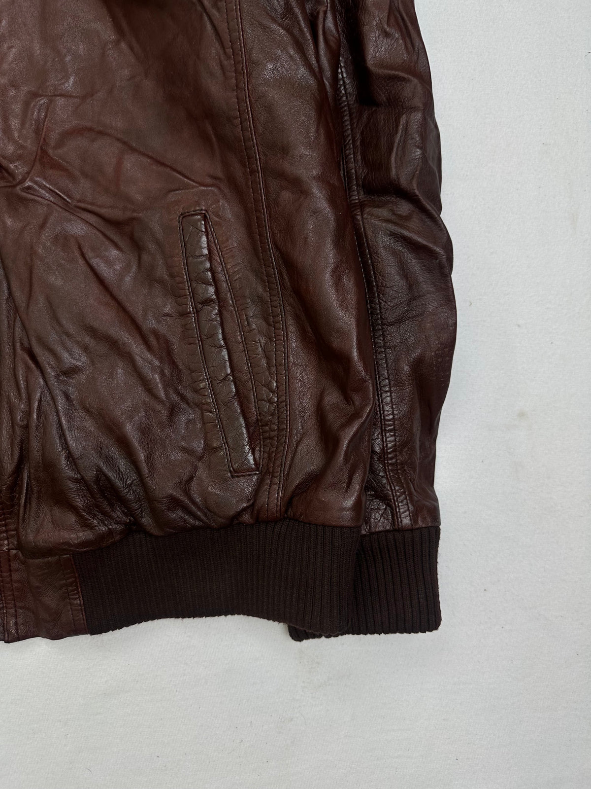 Side pocket and hem of the size XL burgundy leather bomber jacket, up close