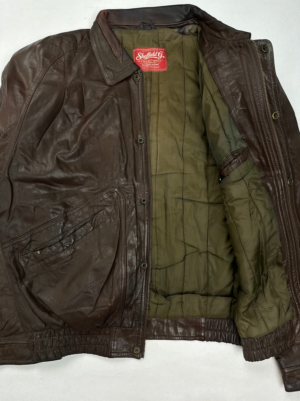 Olive green quilted lining shown with the jacket held open