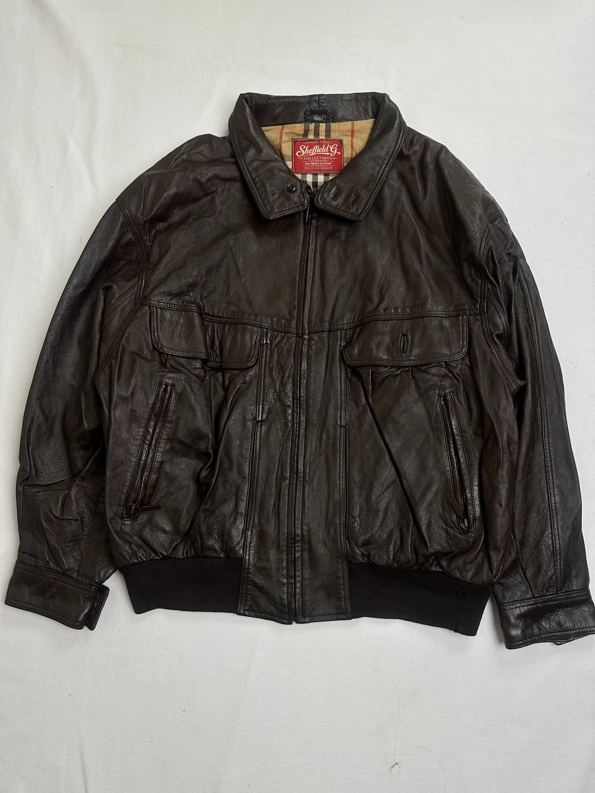Back of the size L brown flight jacket laid flat above its rib hem