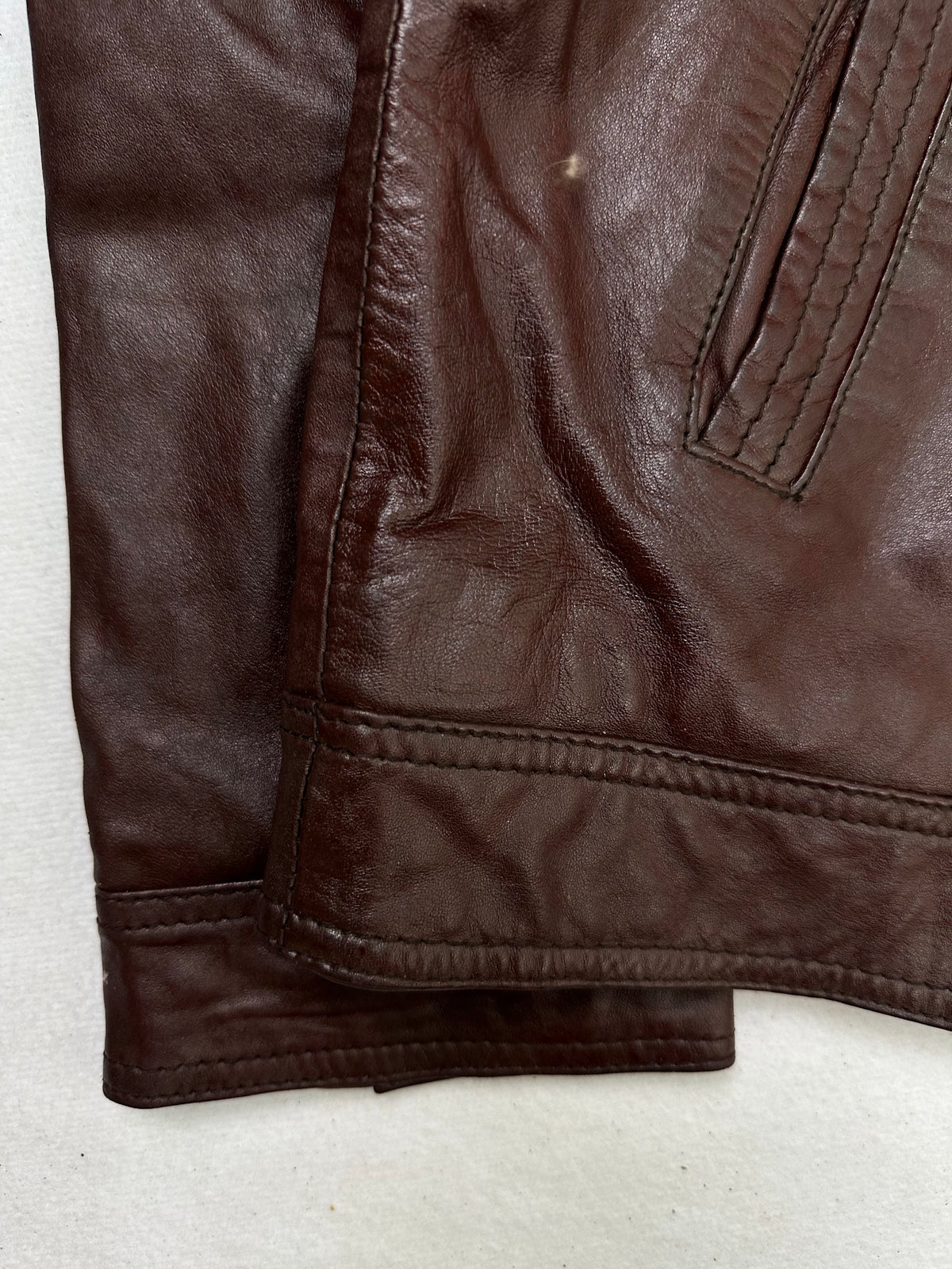 Close detail of the pockets and cuff on the size L burgundy leather cafe racer jacket
