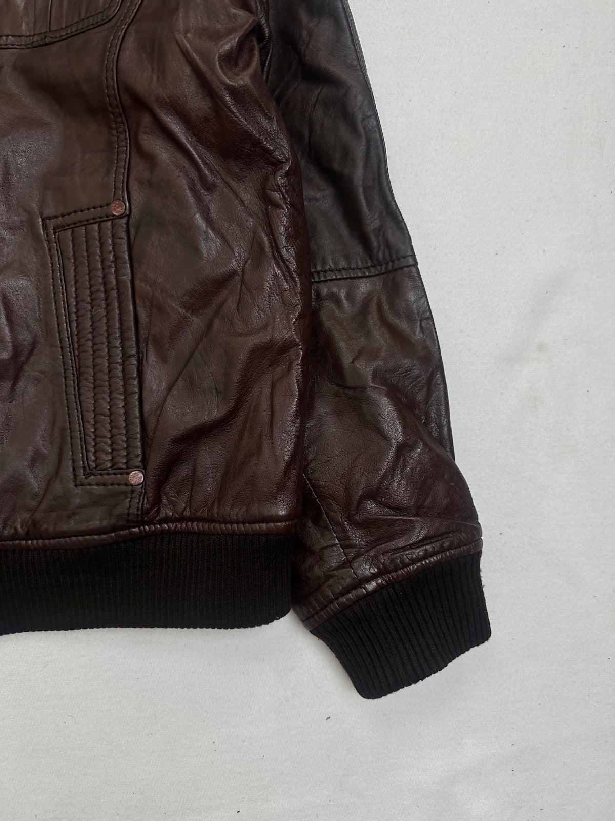 Side pocket and hem of the size L burgundy leather bomber jacket, up close