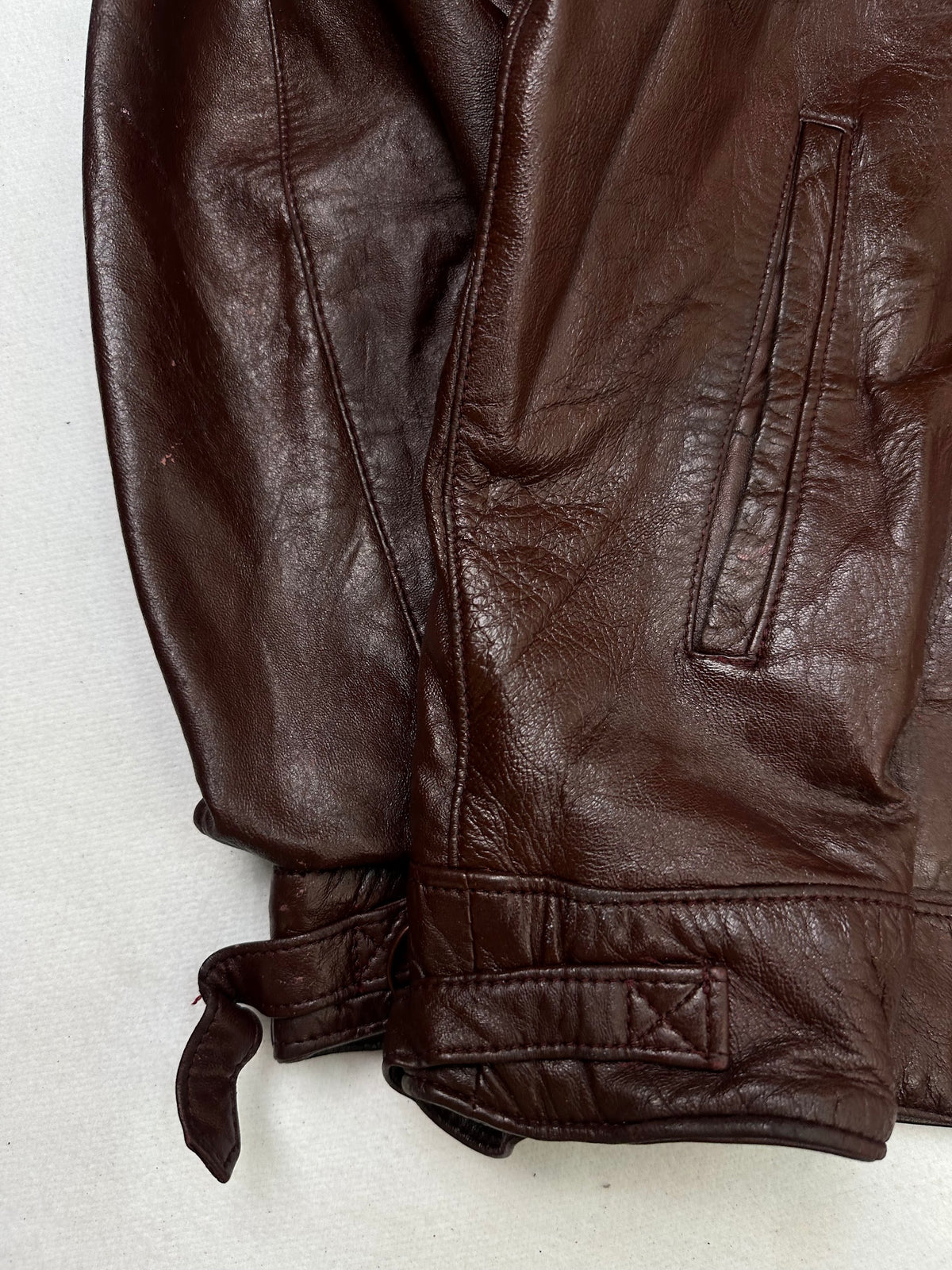Close detail of the pockets and cuff on the size L burgundy leather cafe racer jacket
