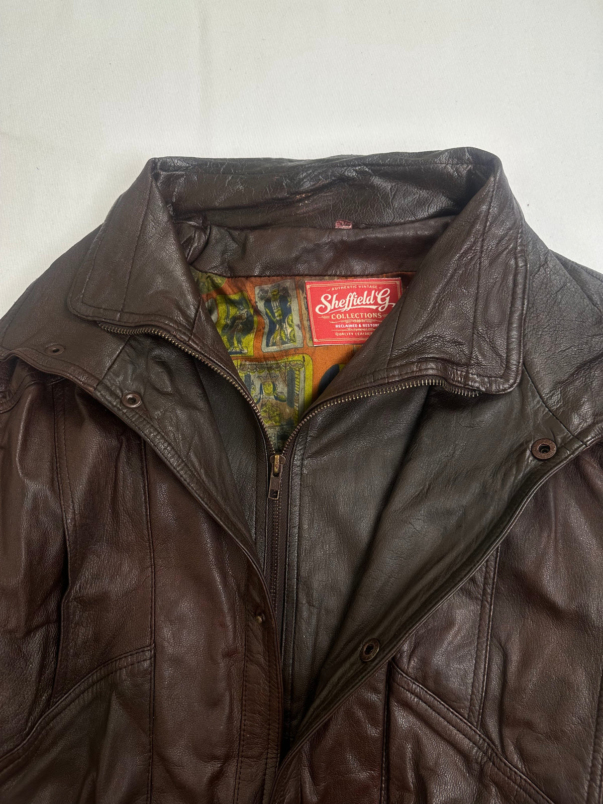 Pointed shirt collar over the snap storm placket on the brown harrington