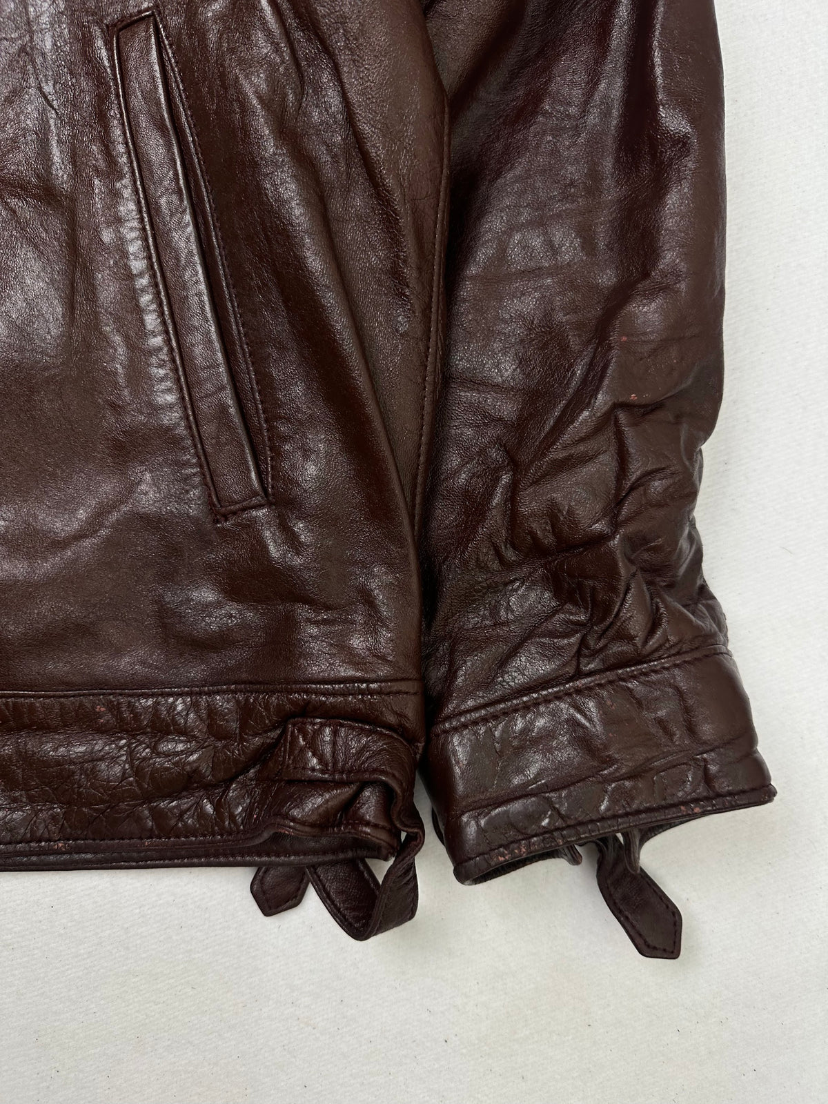 Side pocket and hem of the size L burgundy leather cafe racer jacket, up close