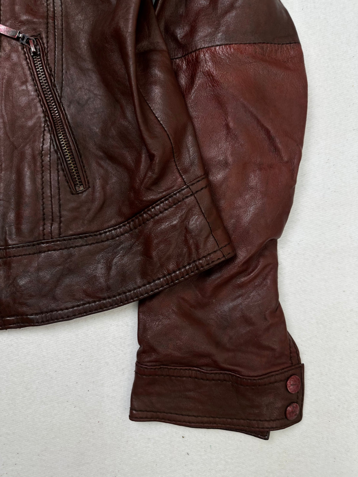 Side pocket and hem of the size S burgundy leather cafe racer jacket, up close