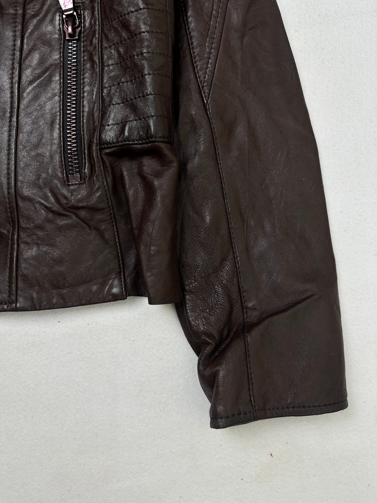 Side pocket and hem of the size XS burgundy leather biker jacket, up close