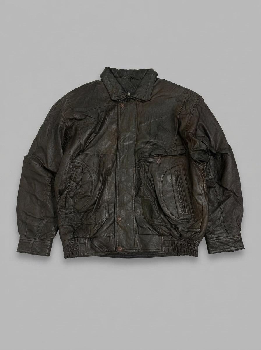 Brown leather flight jacket laid flat, pointed collar with throat latch, snap storm placket and teardrop pocket yokes