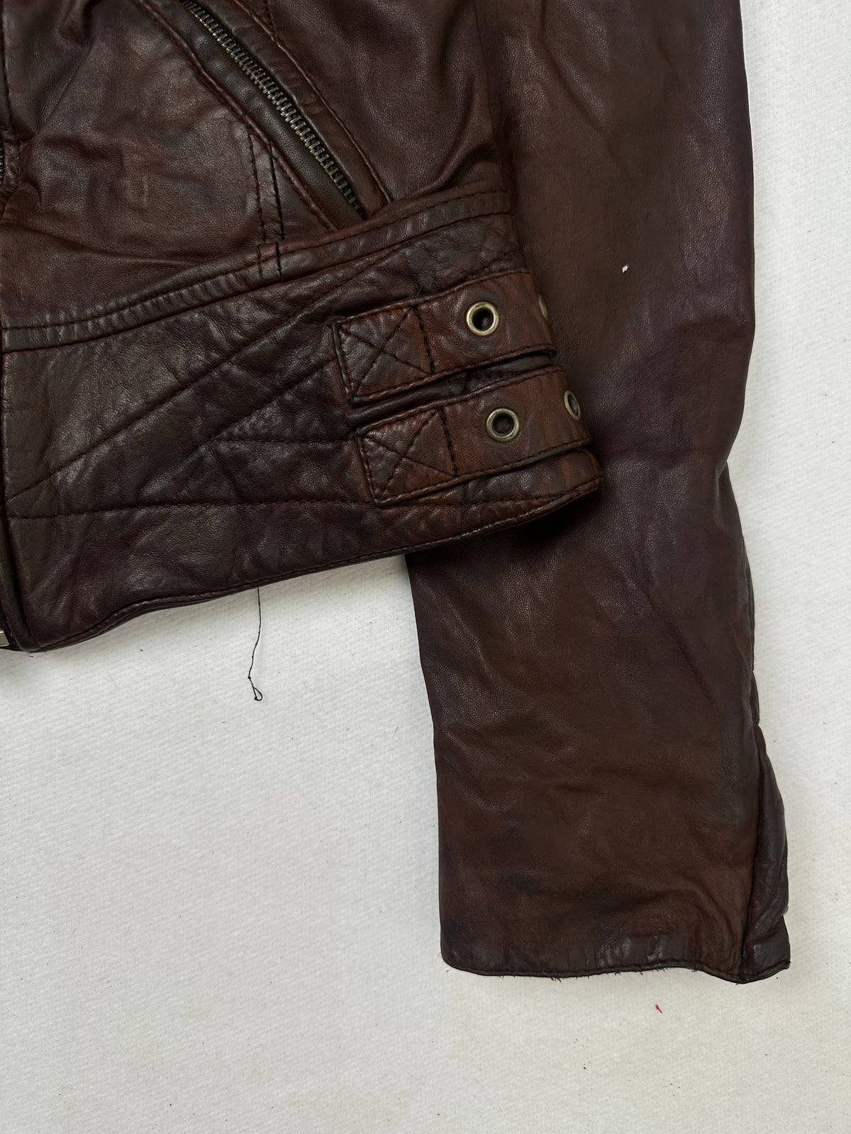 Side pocket and hem of the size S burgundy leather biker jacket, up close