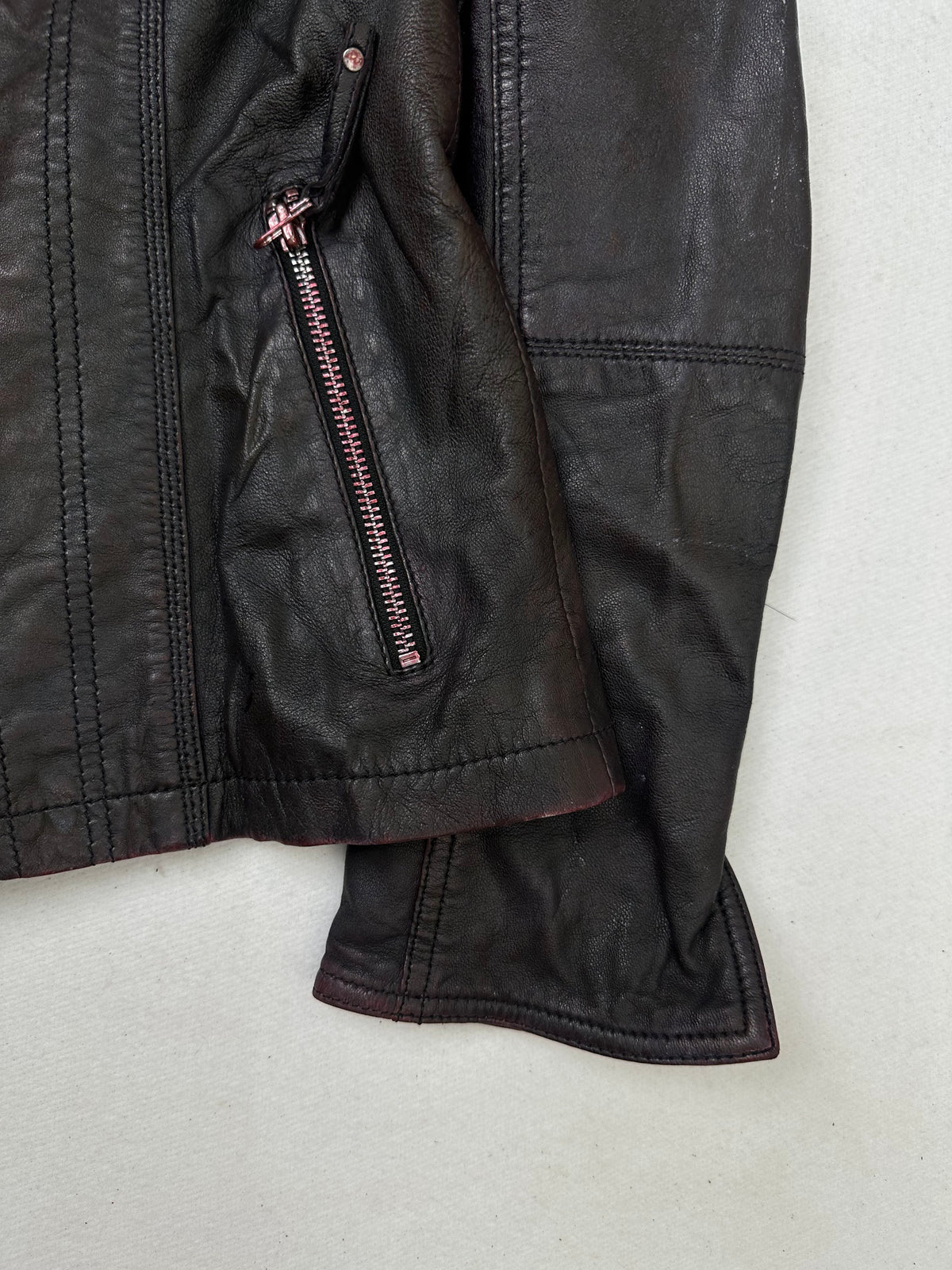 Side pocket and hem of the size S burgundy leather cafe racer jacket, up close