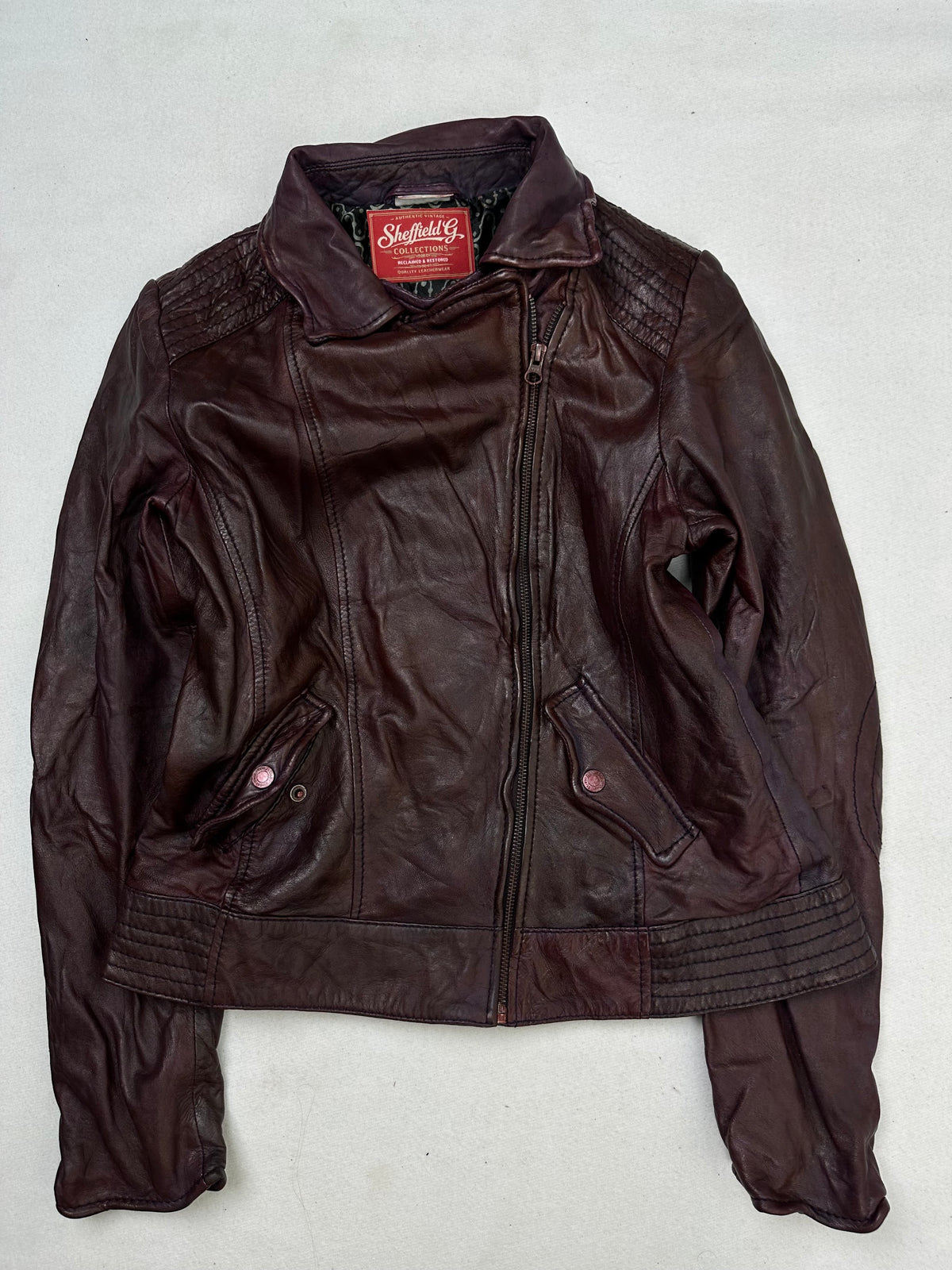 Front of the size S burgundy leather biker jacket, laid flat and unedited