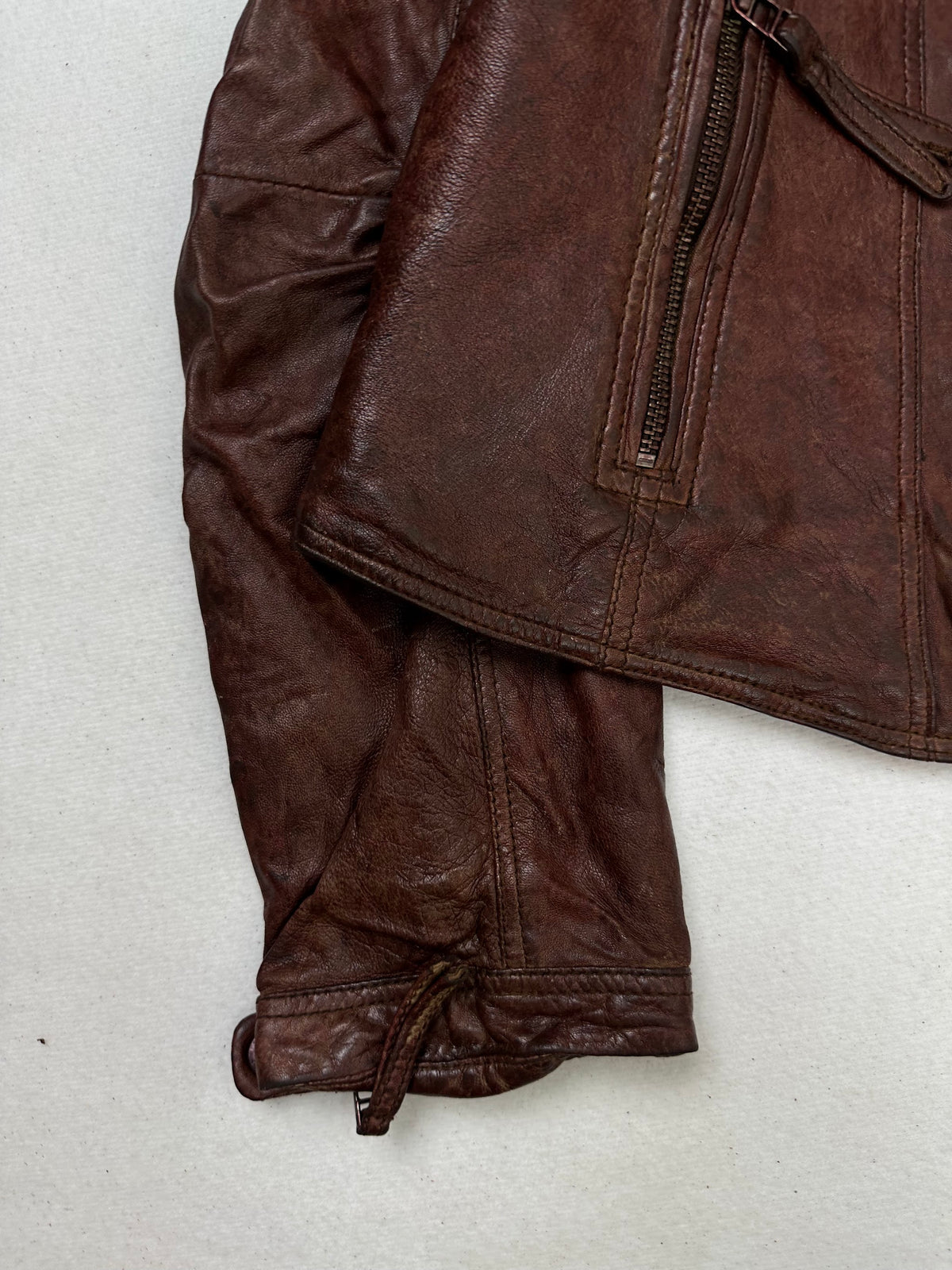 Close detail of the pockets and cuff on the size S burgundy leather biker jacket