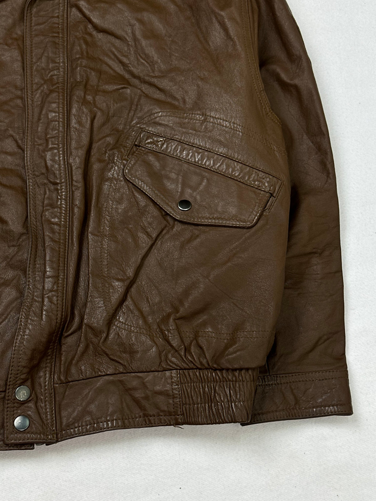 Side pocket and hem of the size M brown leather flight jacket, up close