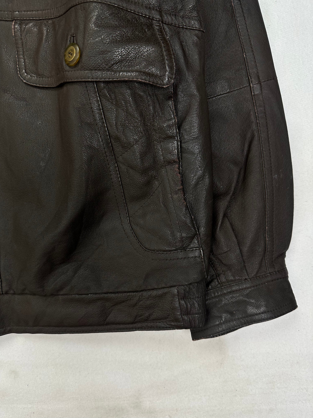 Brass-tone buttoned flap pocket above a curved hand pocket
