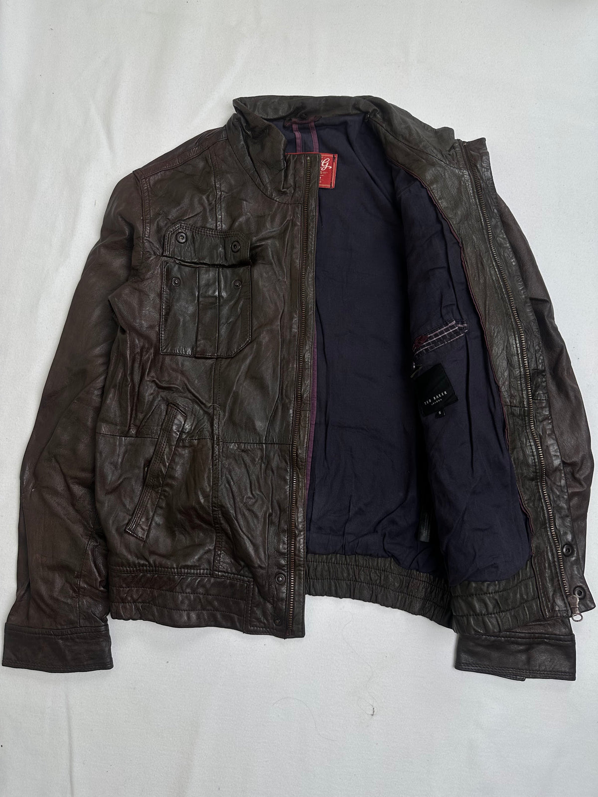 Press stud chest flap pocket above a slanted welt pocket
