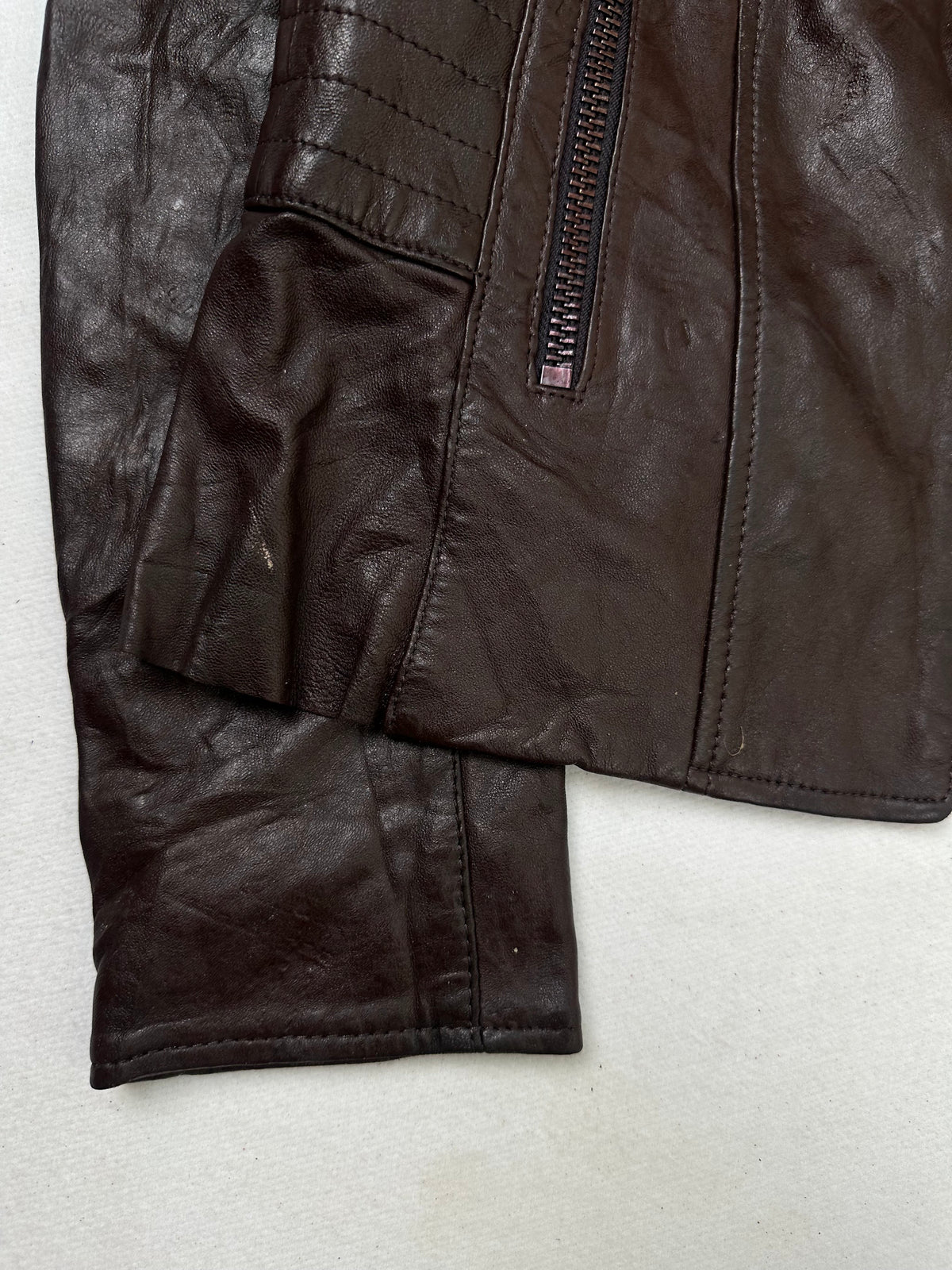 Close detail of the pockets and cuff on the size XS burgundy leather biker jacket