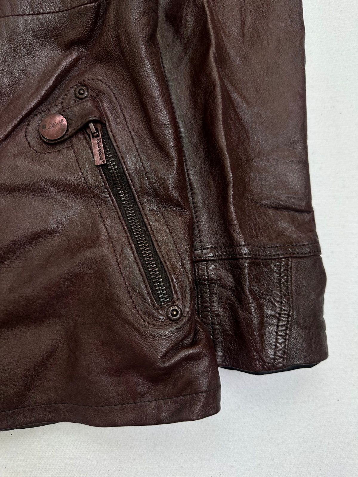 Side pocket and hem of the size M burgundy leather biker jacket, up close