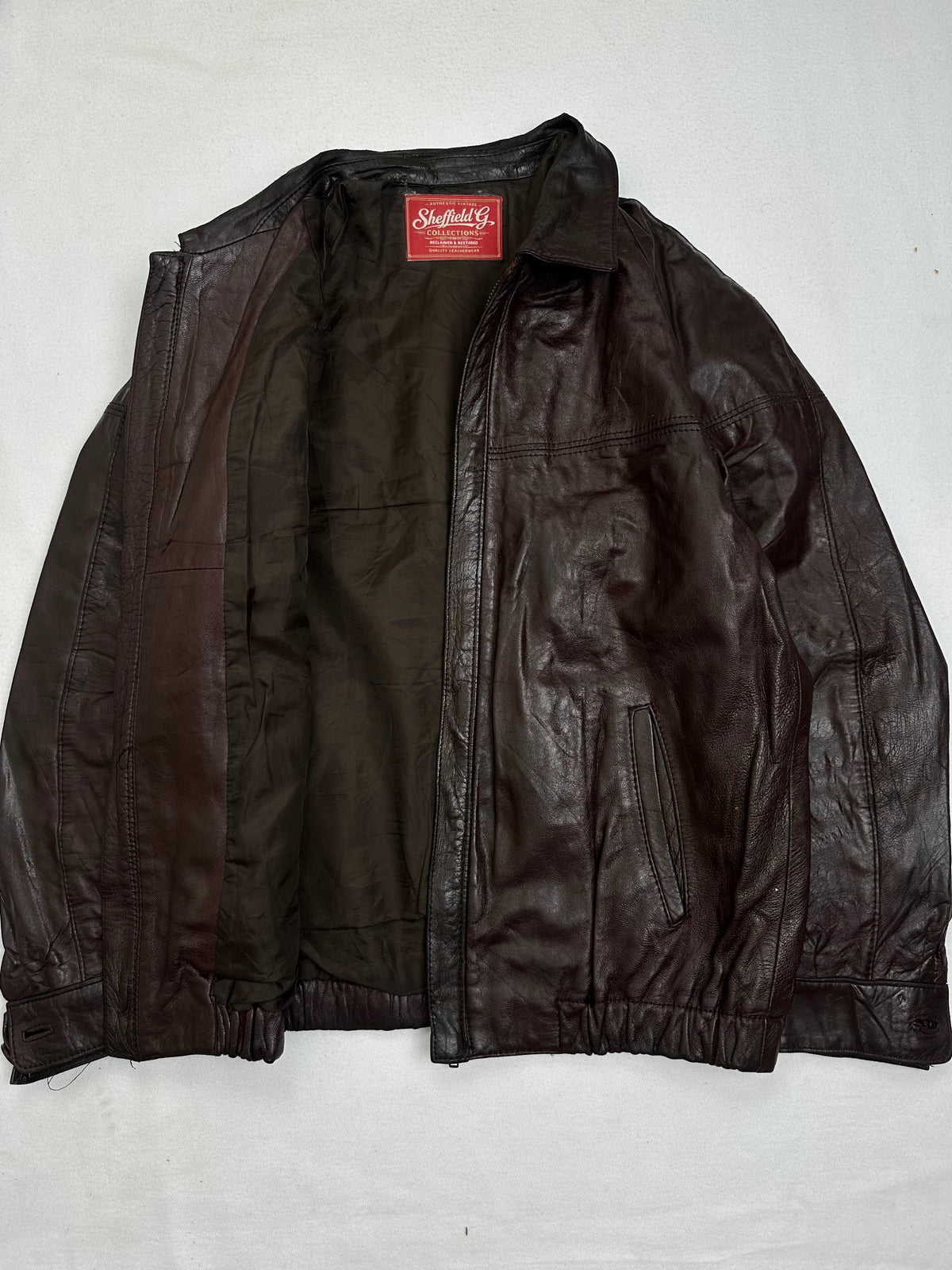 The size M burgundy leather harrington jacket opened to show the lining
