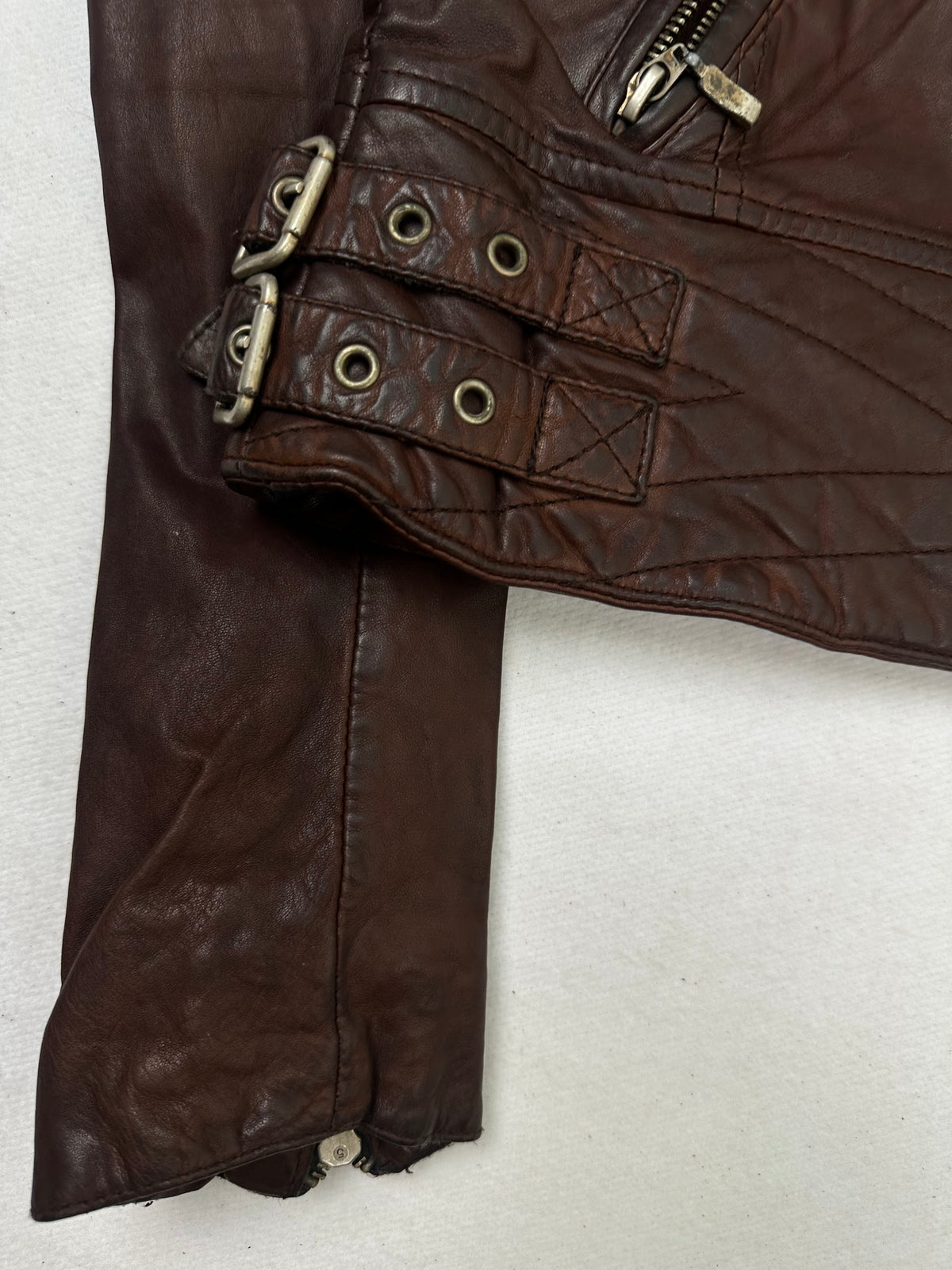 Close detail of the pockets and cuff on the size S burgundy leather biker jacket