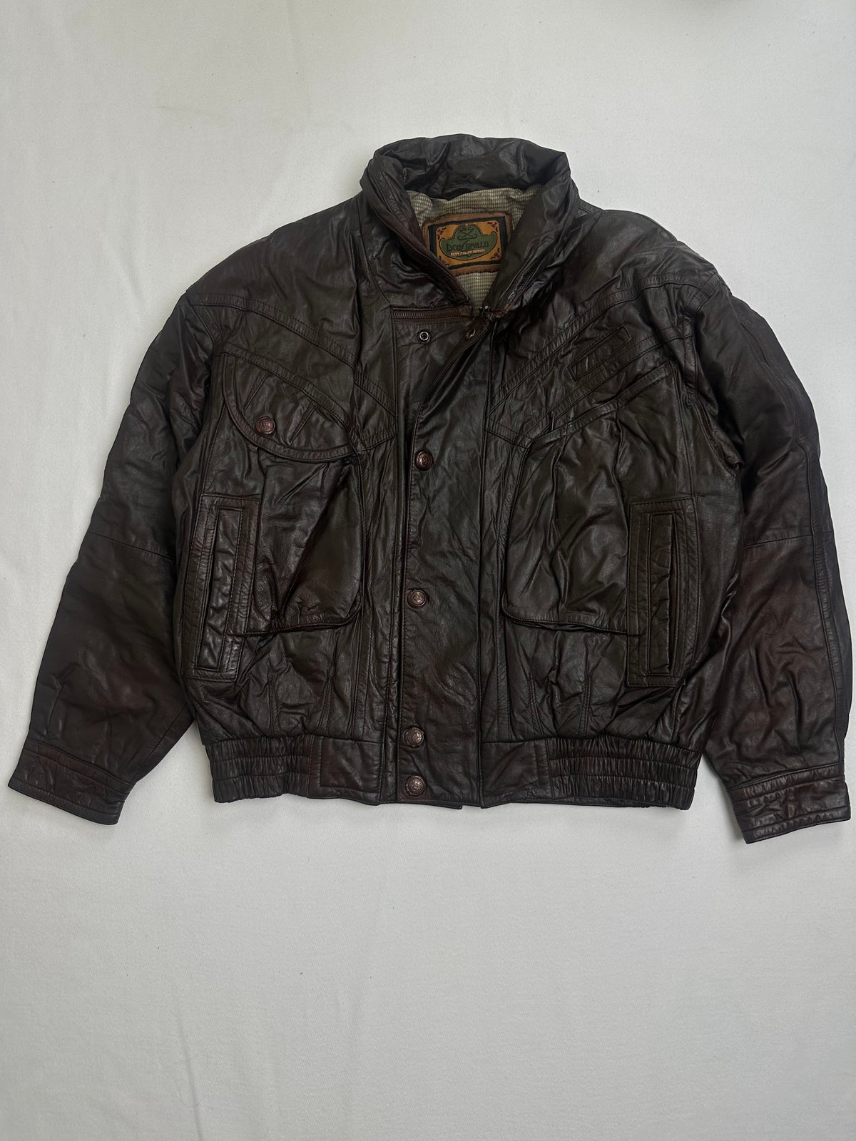 Back of the size L brown flight jacket laid flat with a yoke seam across the shoulders