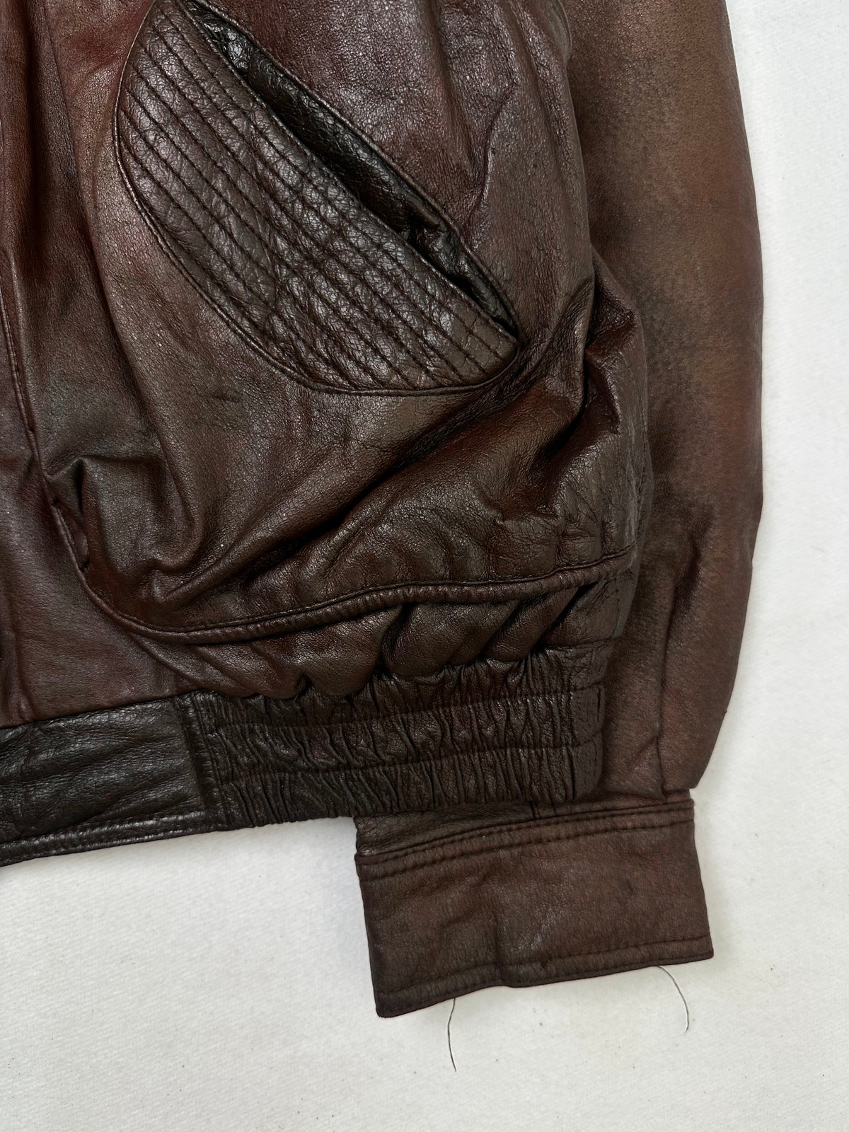 Side pocket and hem of the size L burgundy leather flight jacket, up close