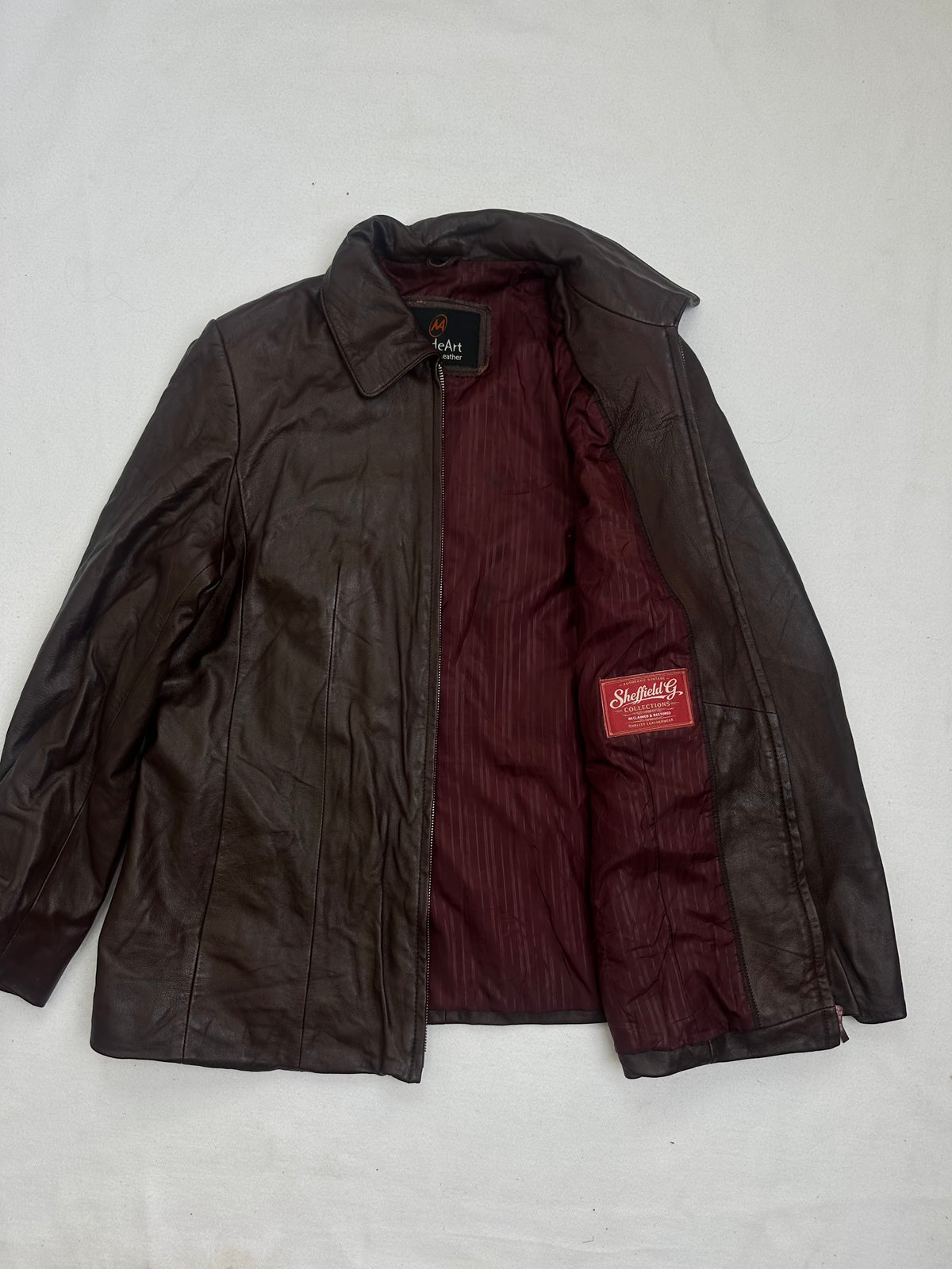 The size L burgundy leather vintage jacket opened to show the lining