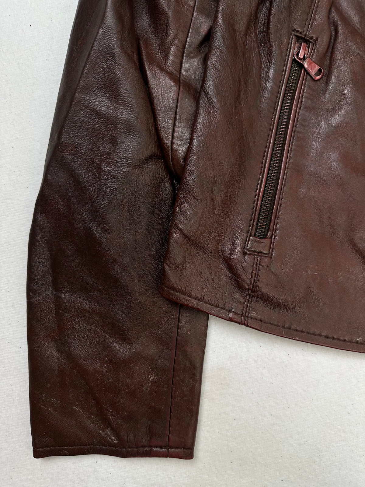 Close detail of the pockets and cuff on the size XS burgundy leather cafe racer jacket