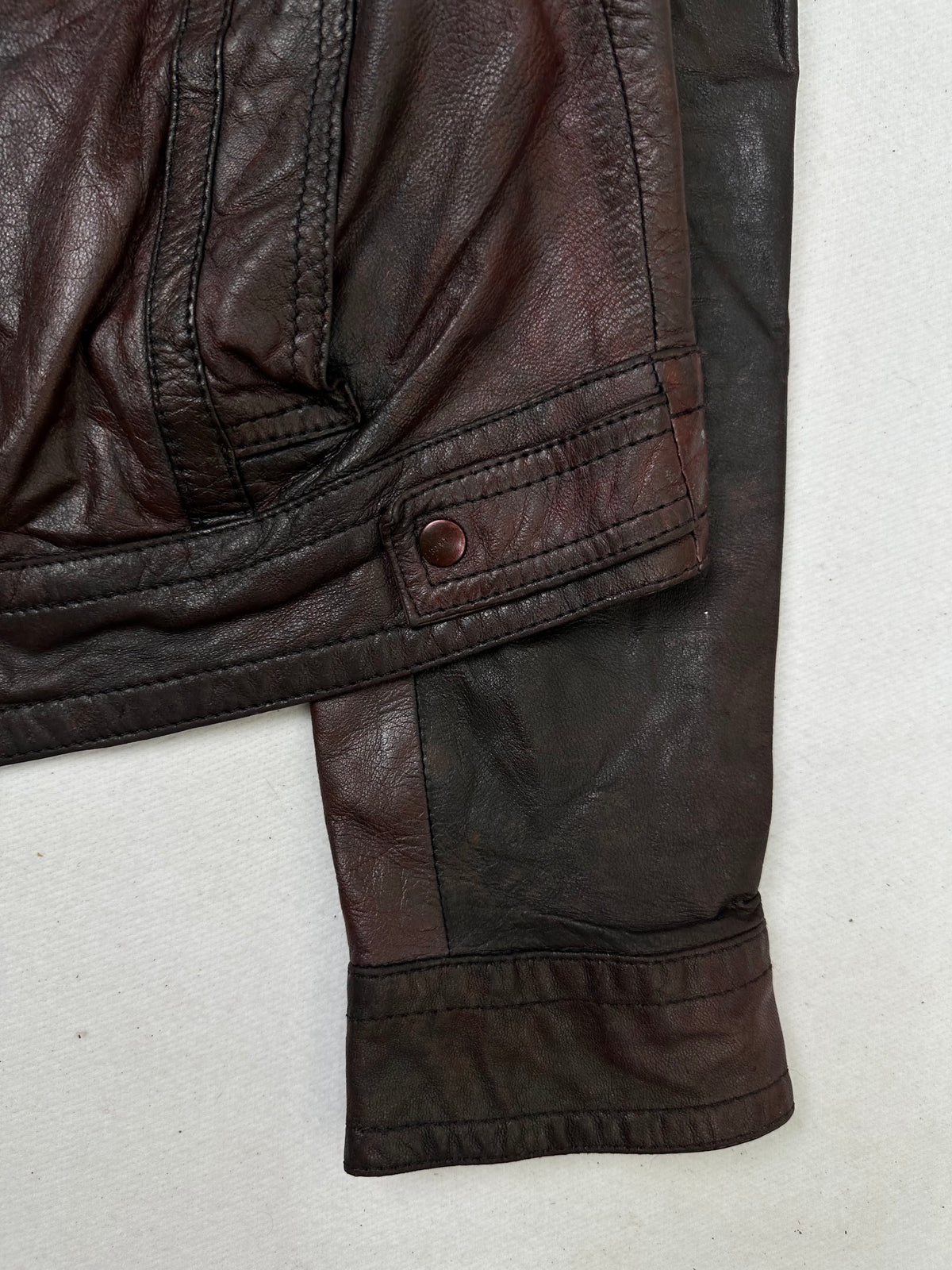 Side pocket and hem of the size S burgundy leather cafe racer jacket, up close
