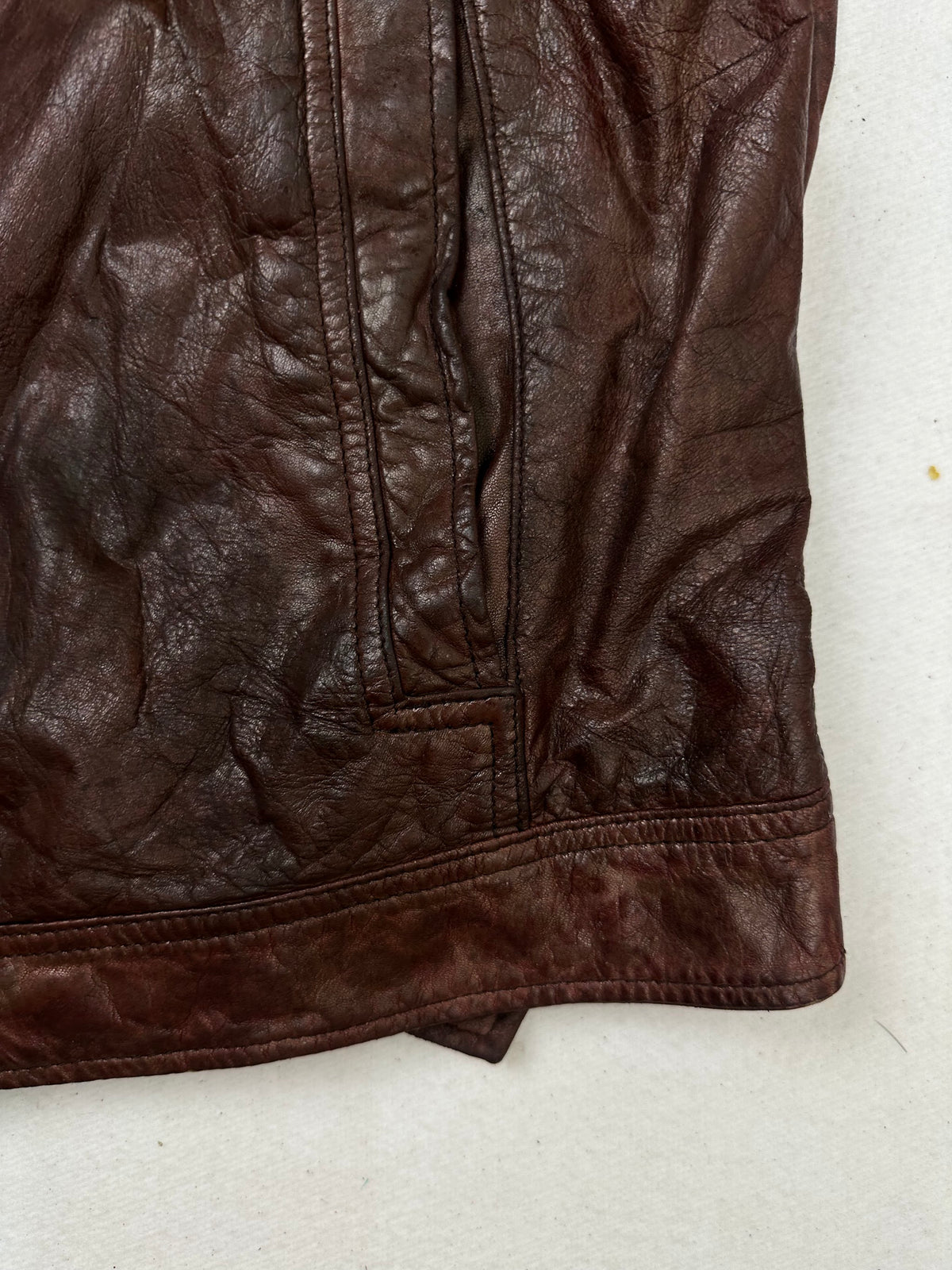 Side pocket and hem of the size L burgundy leather vintage jacket, up close