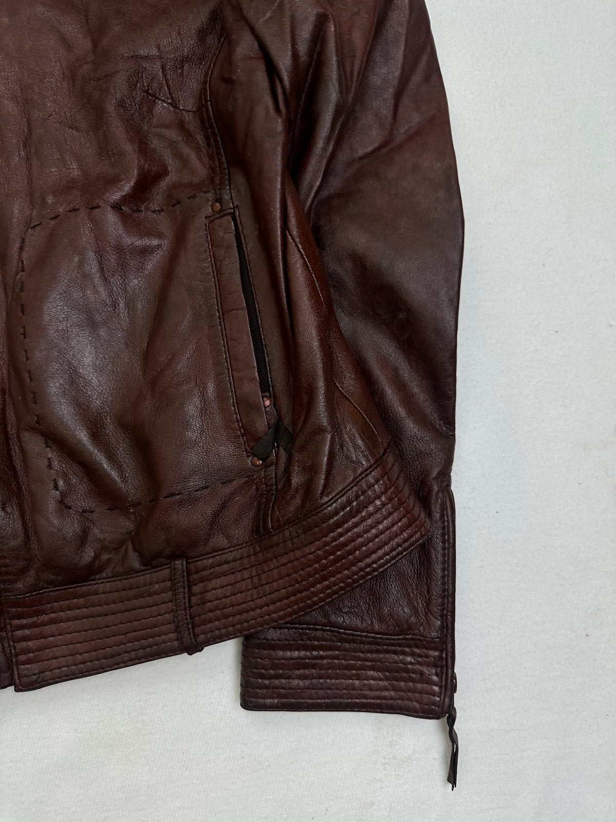 Side pocket and hem of the size S burgundy leather cafe racer jacket, up close